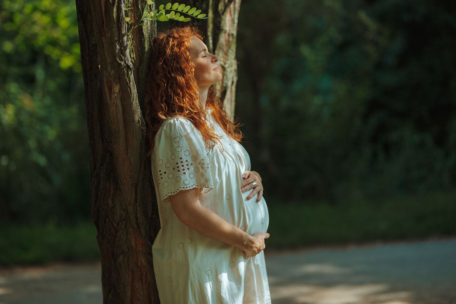 Romantic outdoor photoshoot with white lace dress against natural backdrop.