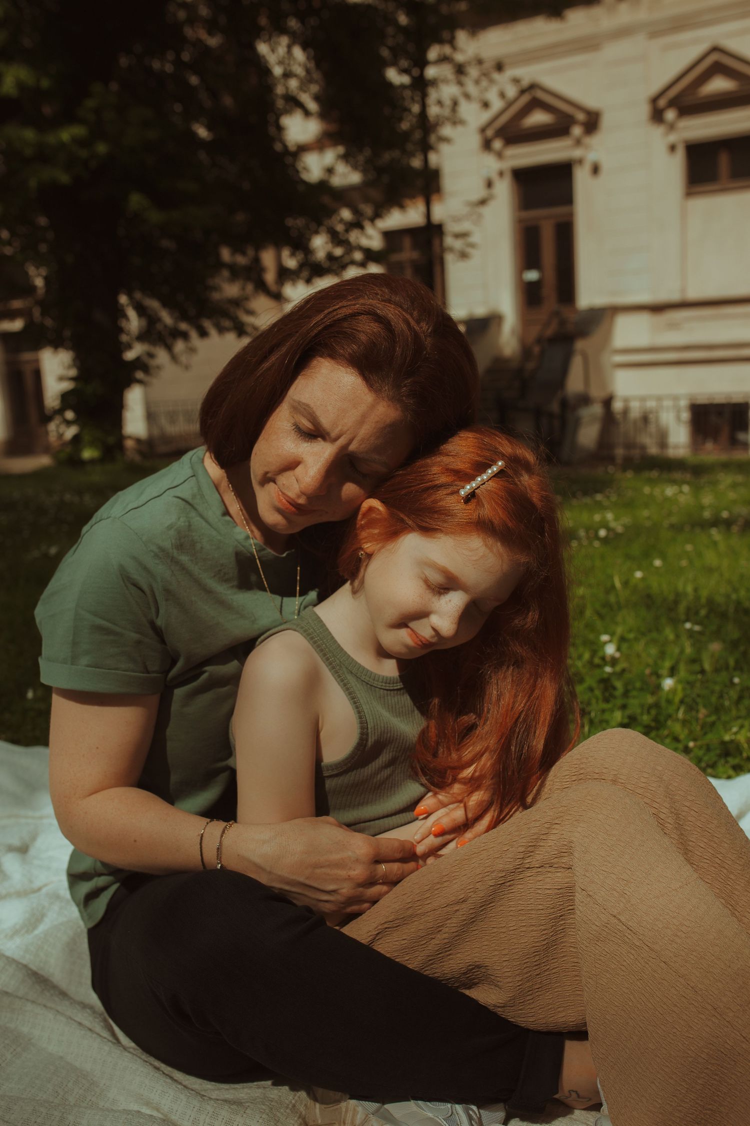 A tender moment between two people relaxing on a blanket in a sunny garden.