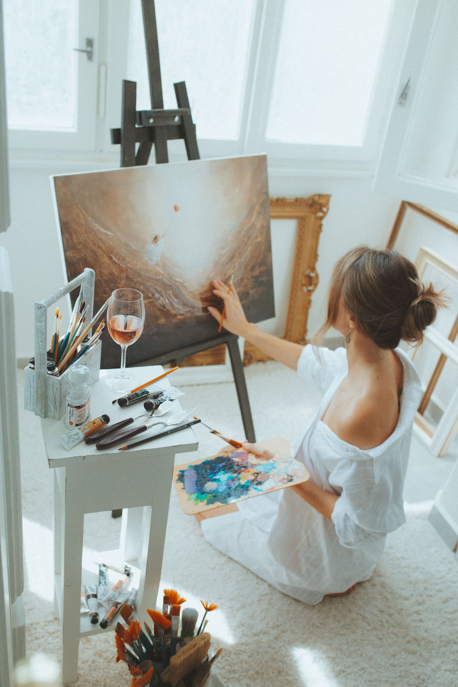 Series of artistic shots showing painter working in sunlit white studio space.