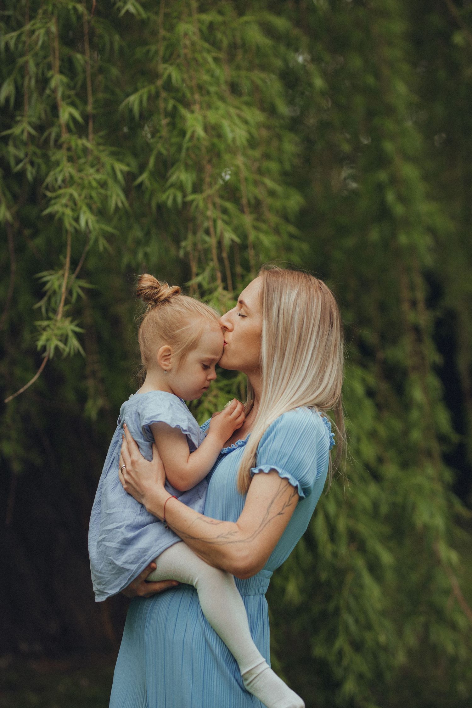 Tender moment between parent and child against bamboo garden backdrop.