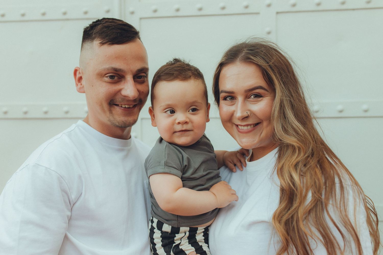 A casual family portrait against a white industrial background.