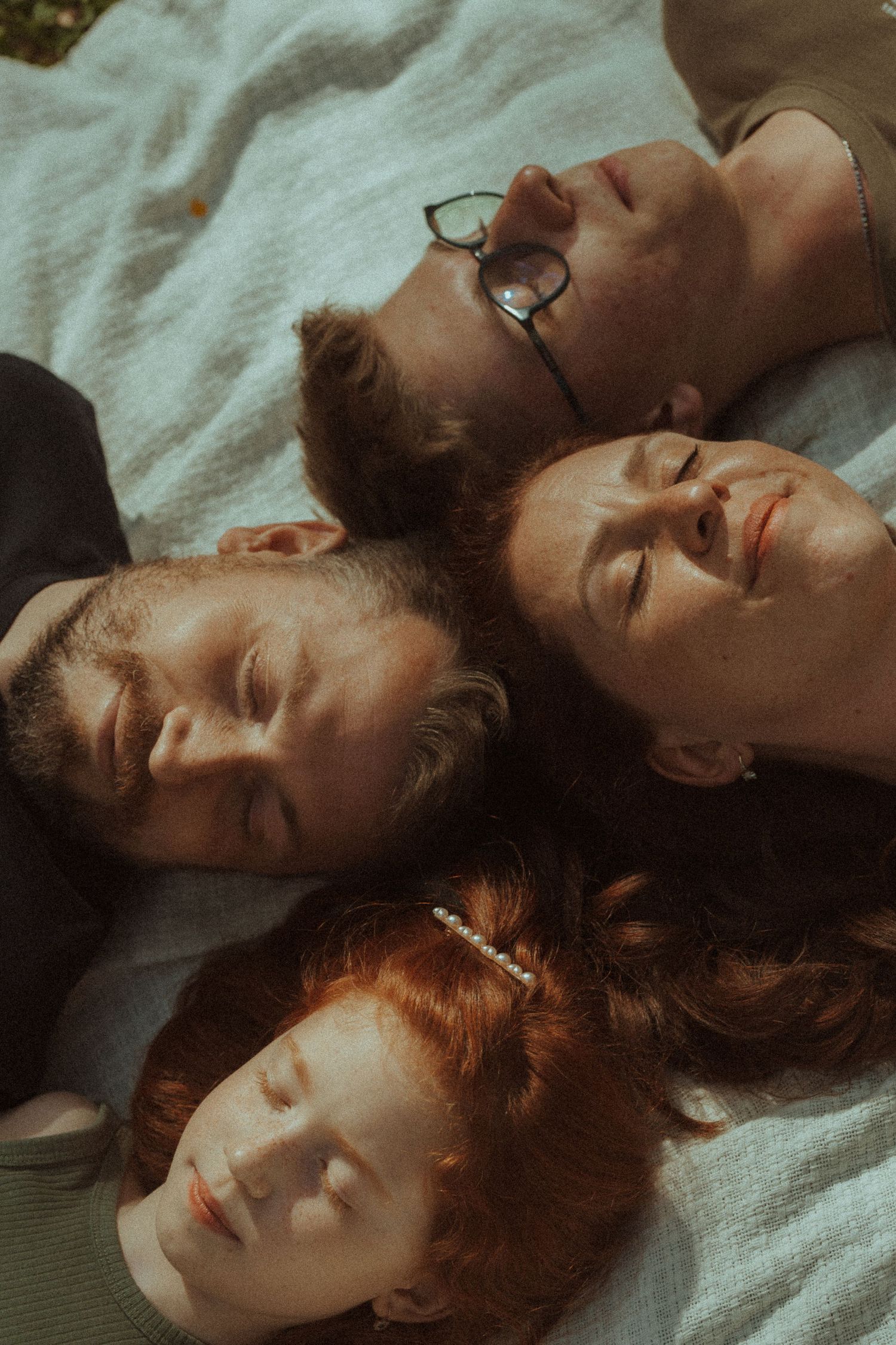 Group of friends laying down together with eyes closed in artistic portrait composition.