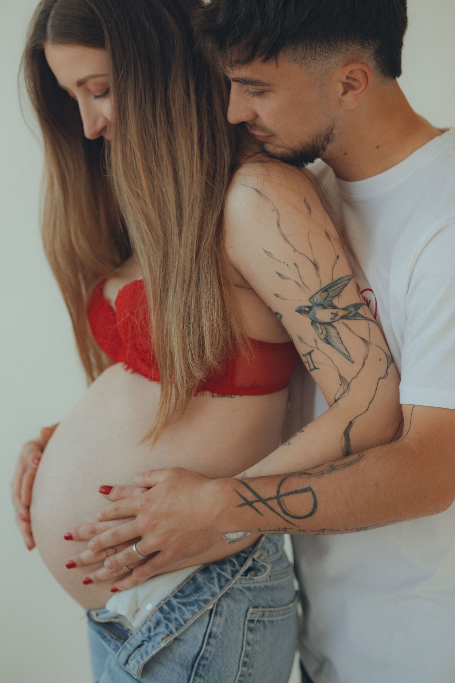 Intimate maternity photo showing couple embracing with visible tattoo art.