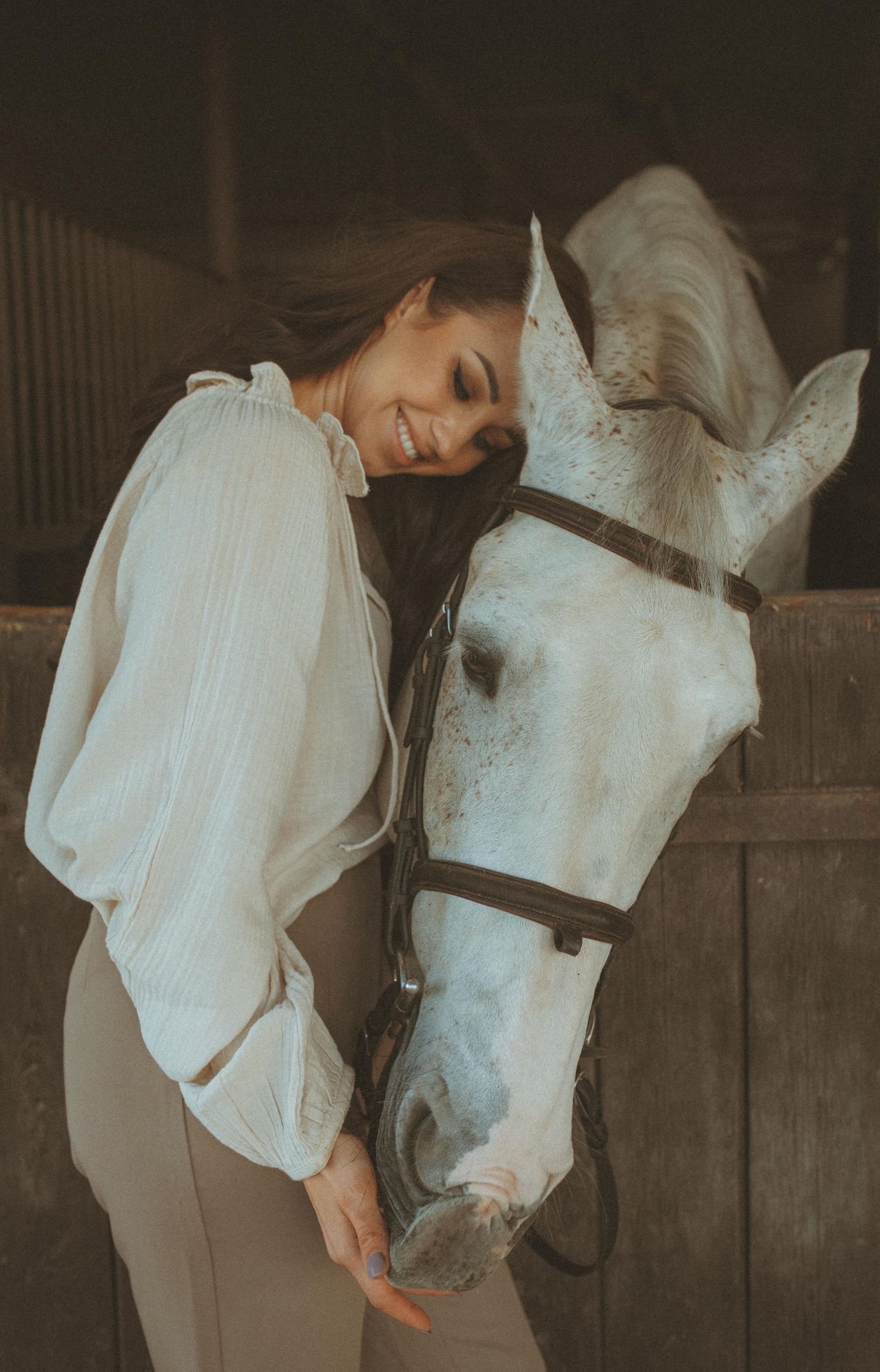 Intimate portrait with a white horse in soft, vintage-style lighting.