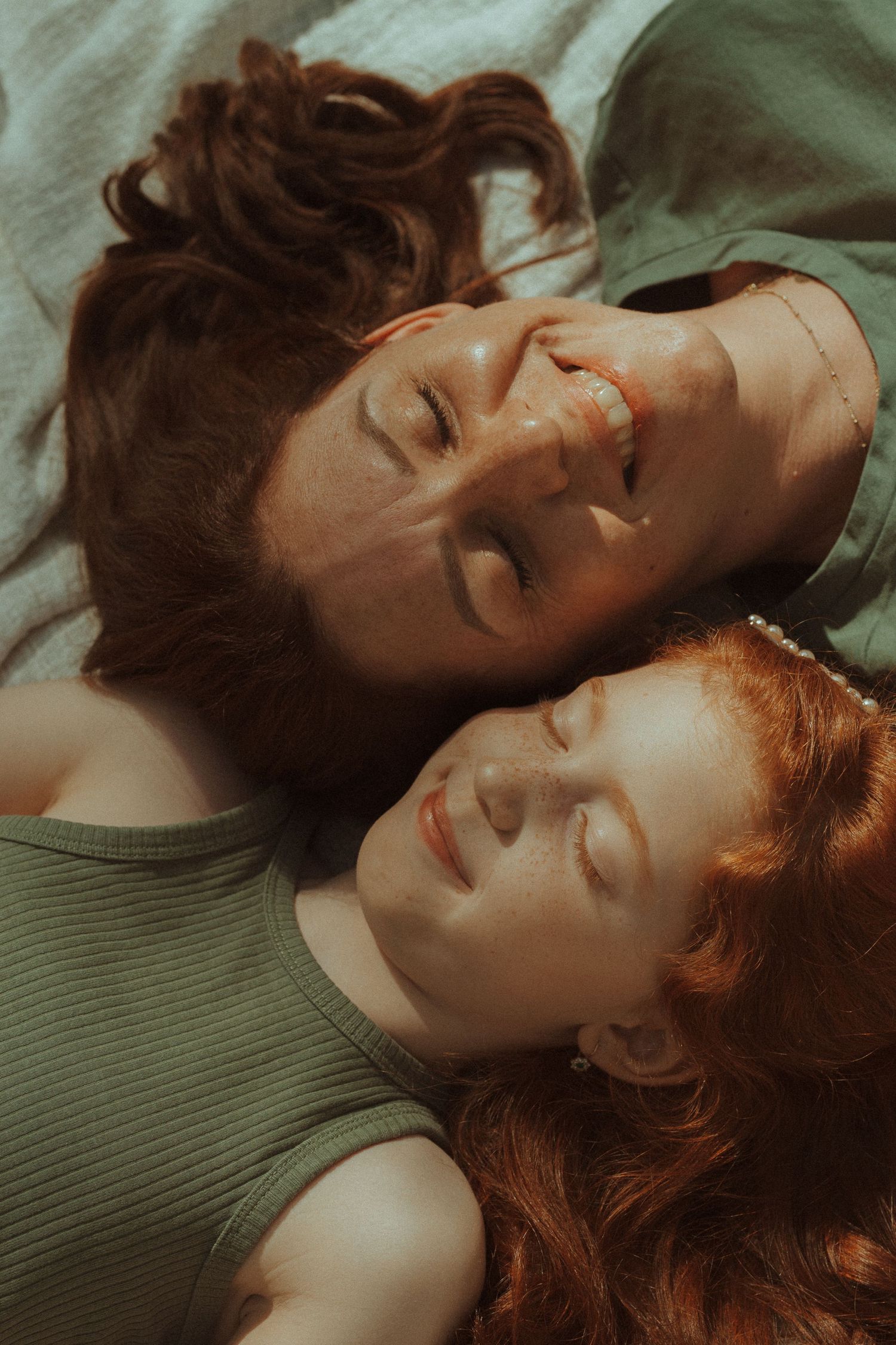 Two friends lying down with their heads together sharing a joyful moment.
