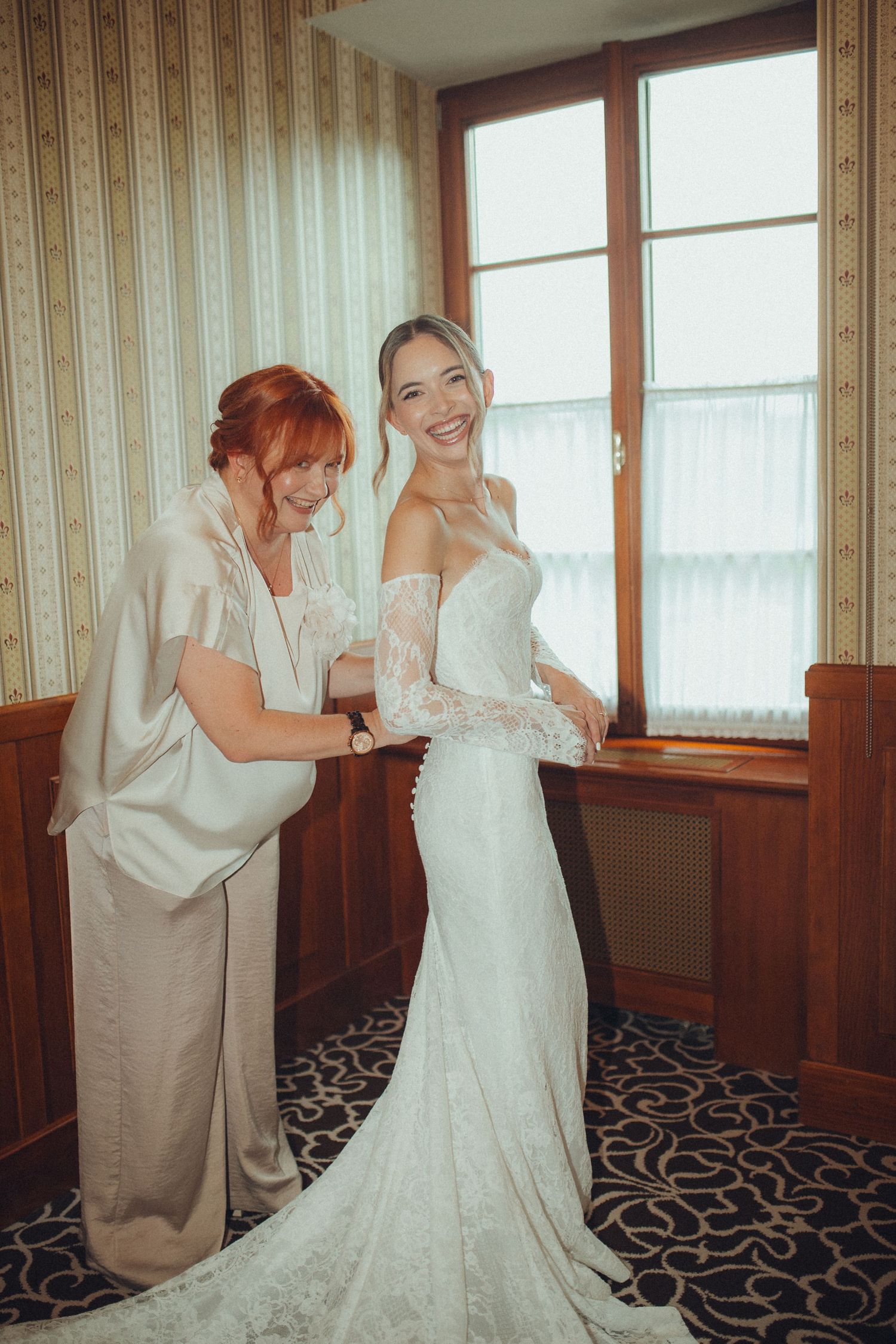 Getting ready moment as bride has final dress adjustments in vintage room.