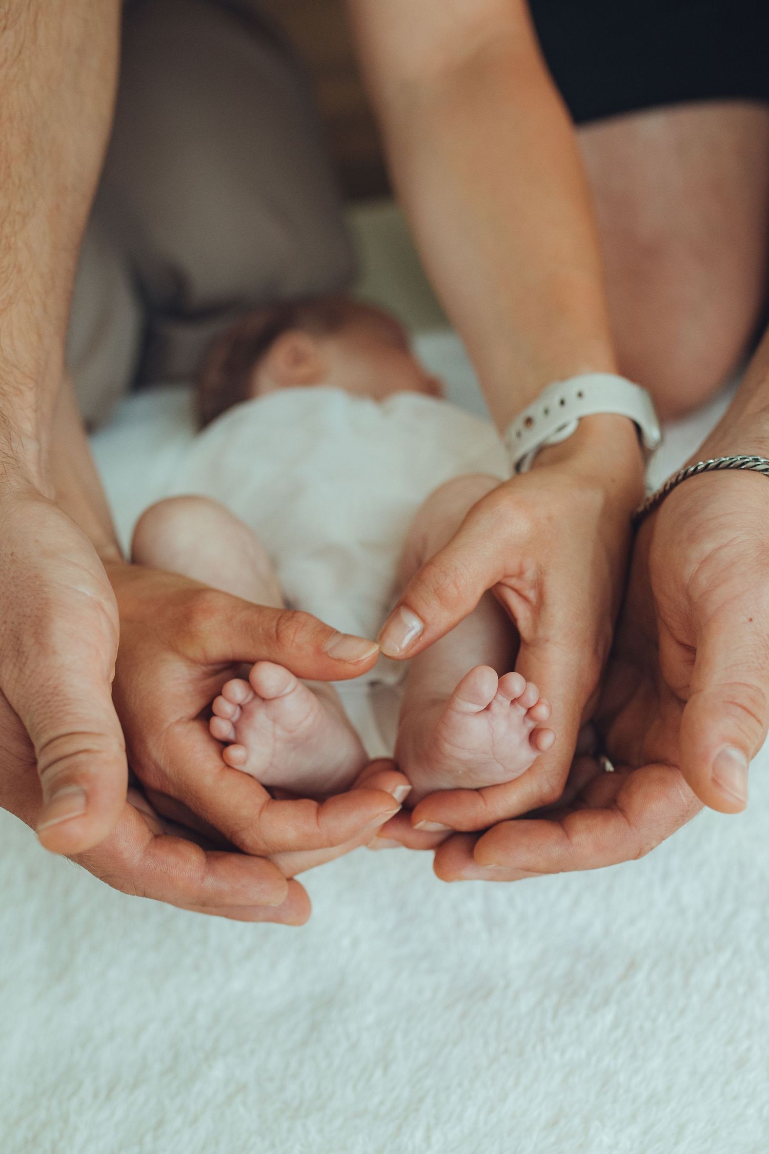 Close-up of tiny newborn baby feet being gently held by adult hands.