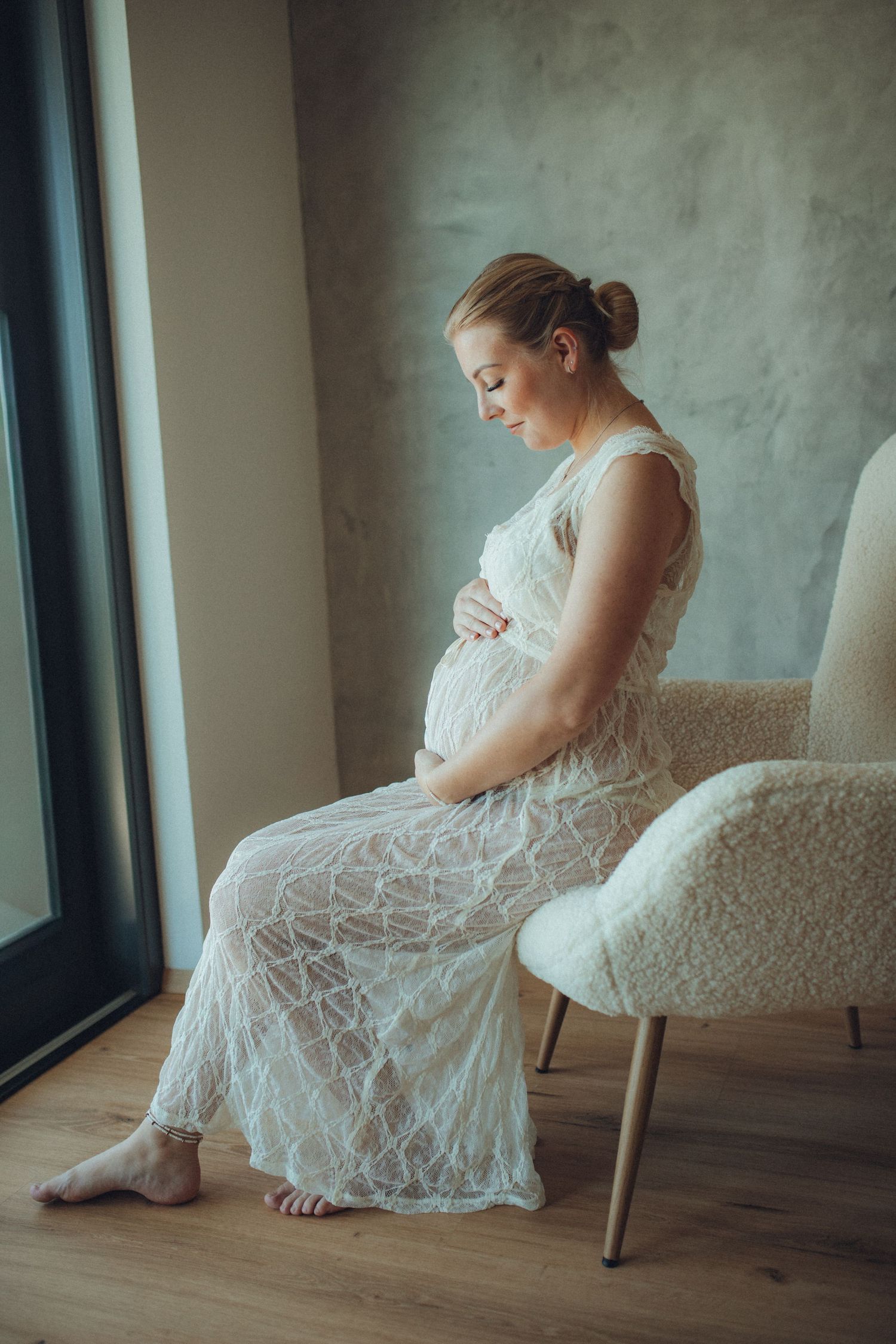 A person in a delicate white lace dress sits gracefully by a window in a series of soft, ethereal poses.