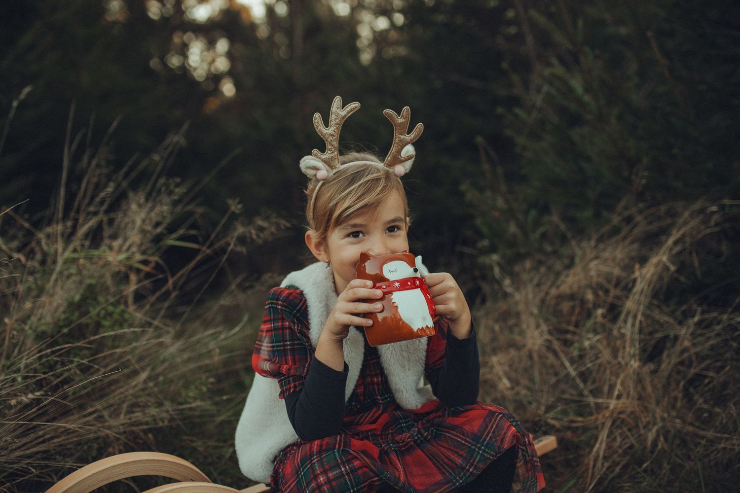 A cozy outdoor family photo session featuring matching plaid and white outfits in a natural setting.