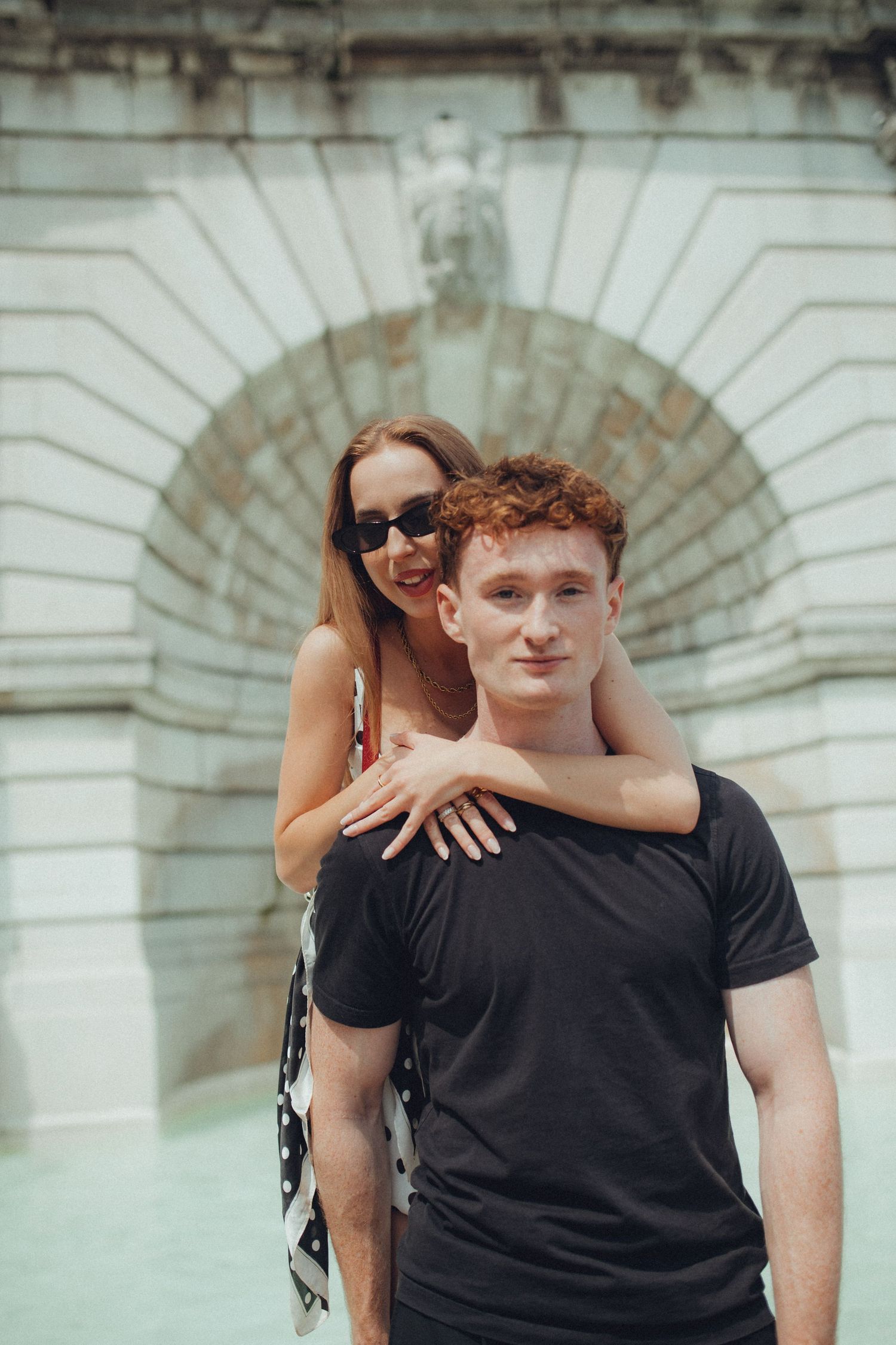 Casual couple portraits against architectural backdrop with arched details.