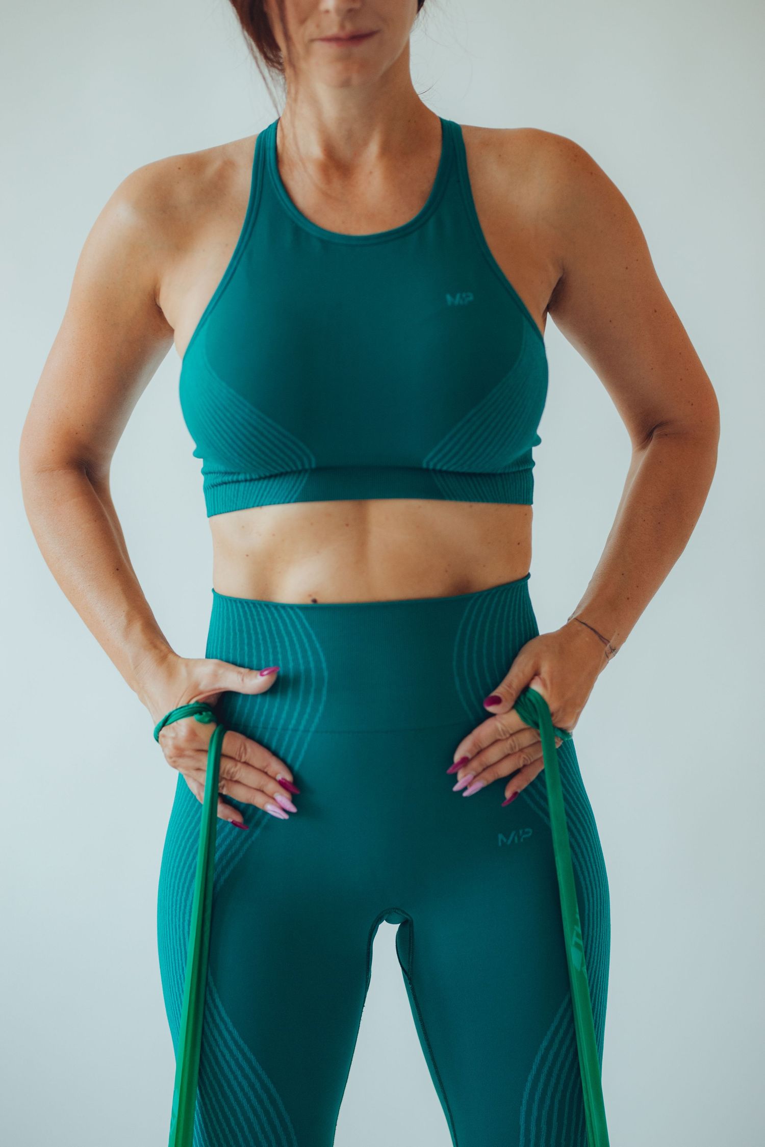 Athletic wear detail showing teal sports bra and high-waisted leggings.