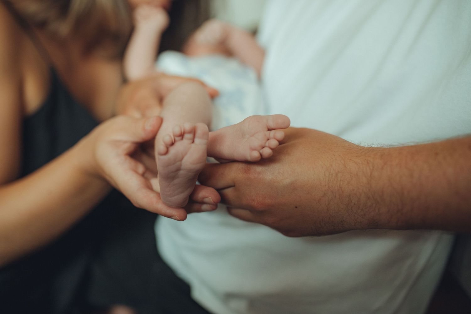 Close-up of baby's tiny feet being held by gentle hands.