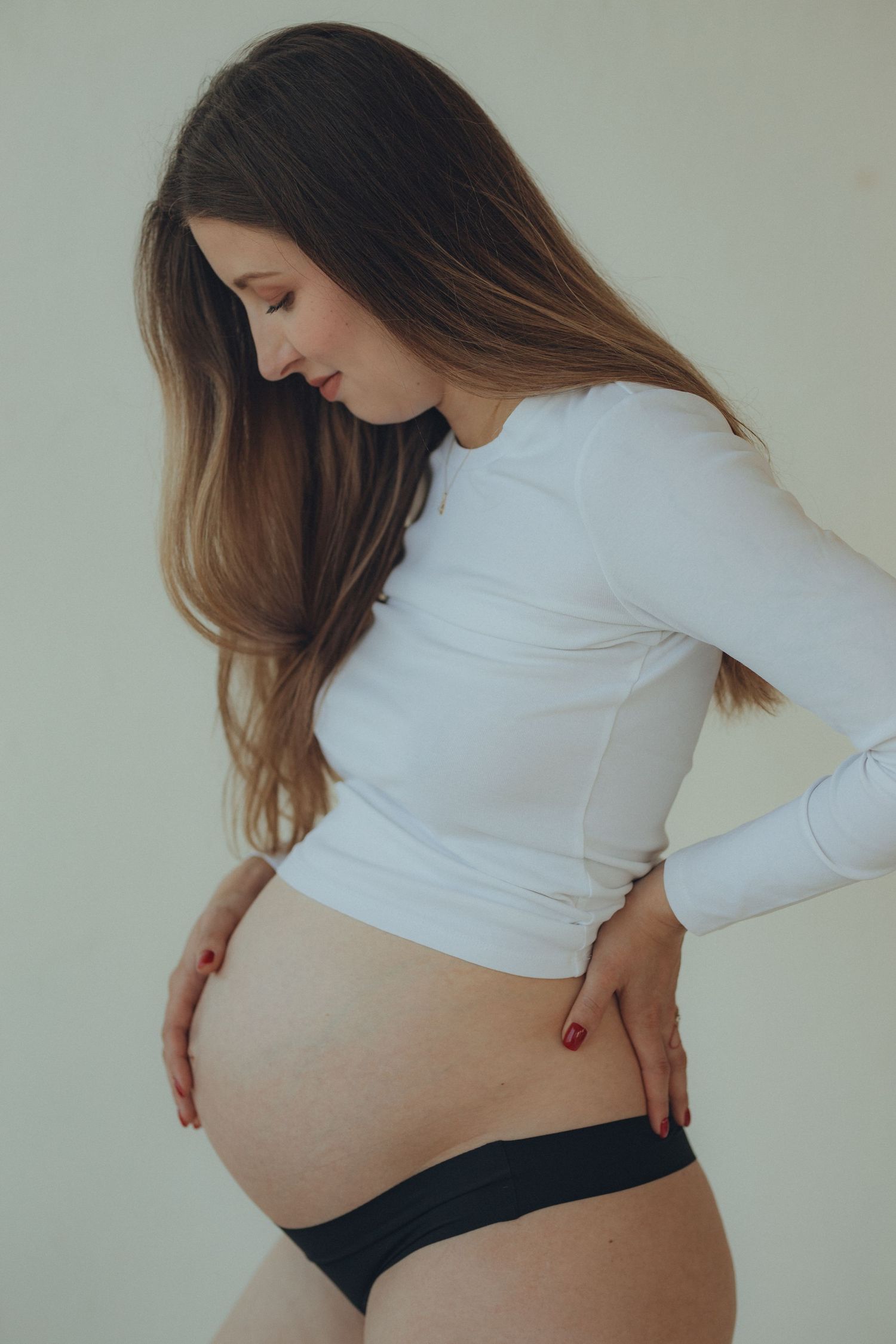 Maternity photo series showing pregnant belly against neutral background.