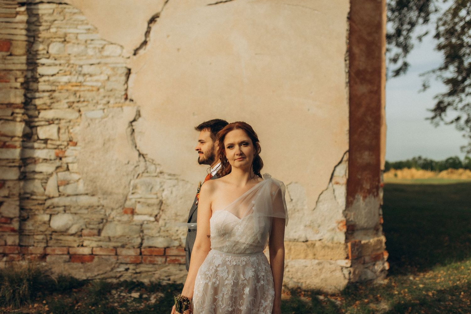 Wedding portraits taken against rustic stone wall at golden hour.