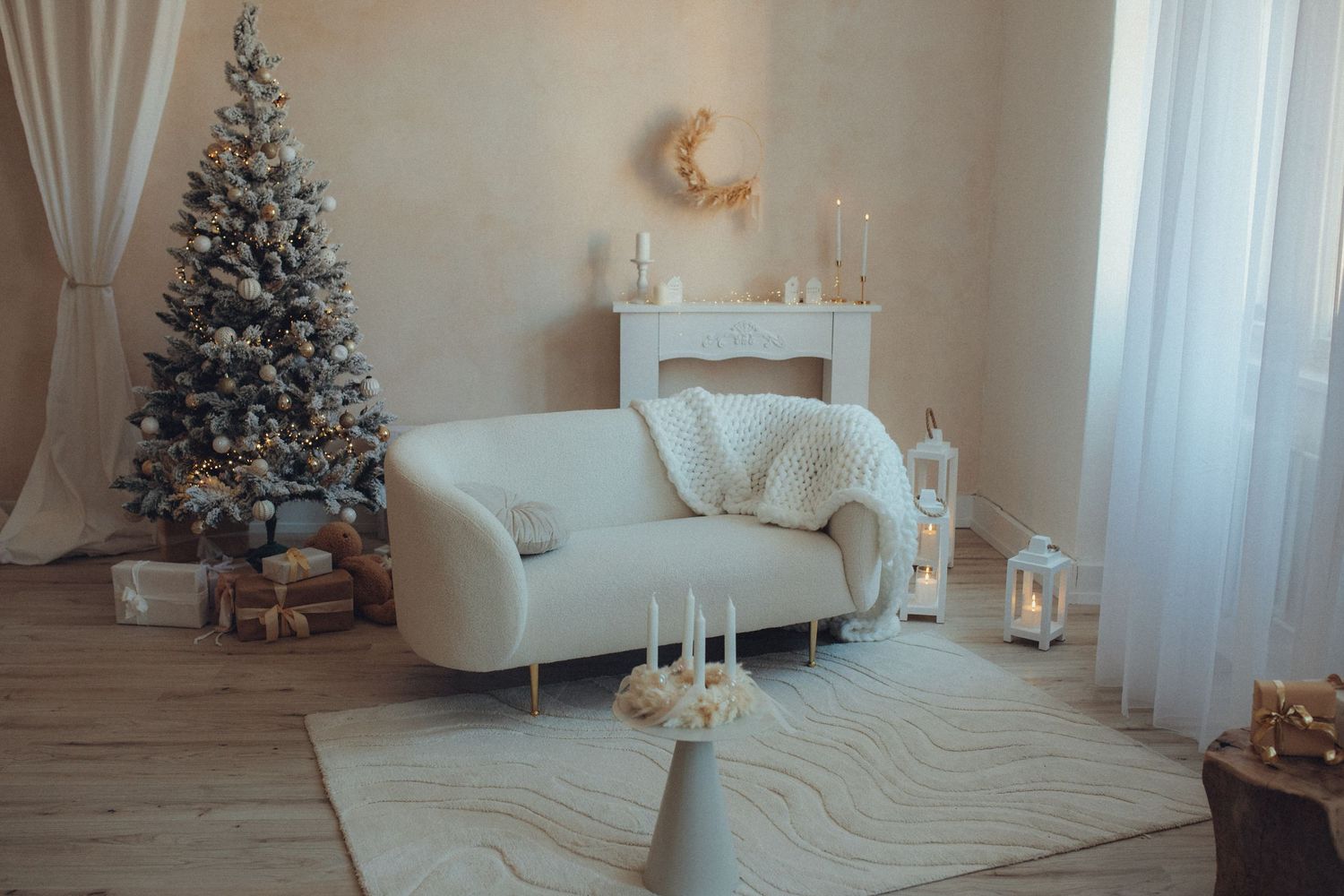 Modern white living room decorated for Christmas with elegant tree, plush sofa, and sheer curtains.