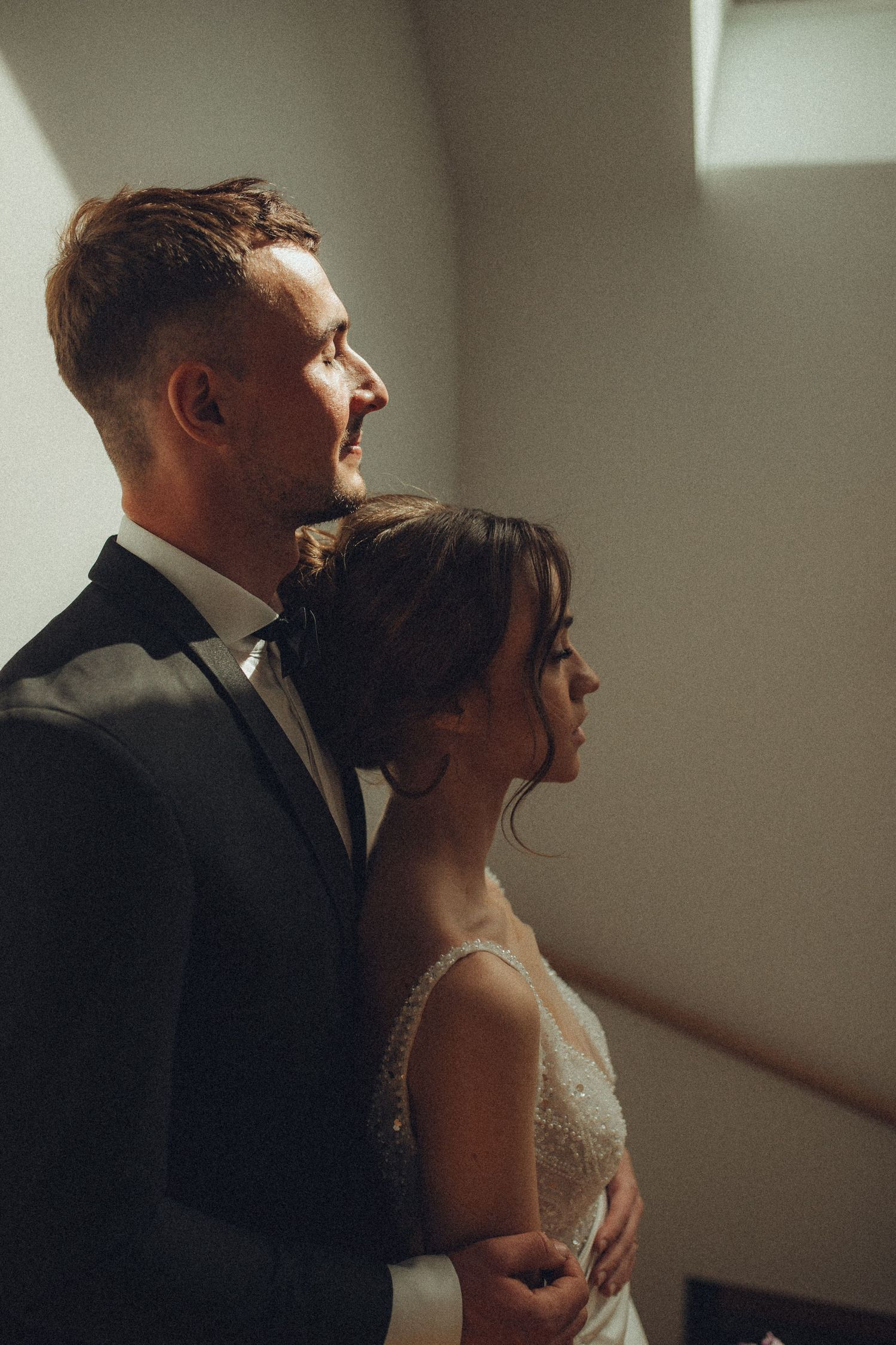 Artistic wedding photography showing tender moments in moody lighting.