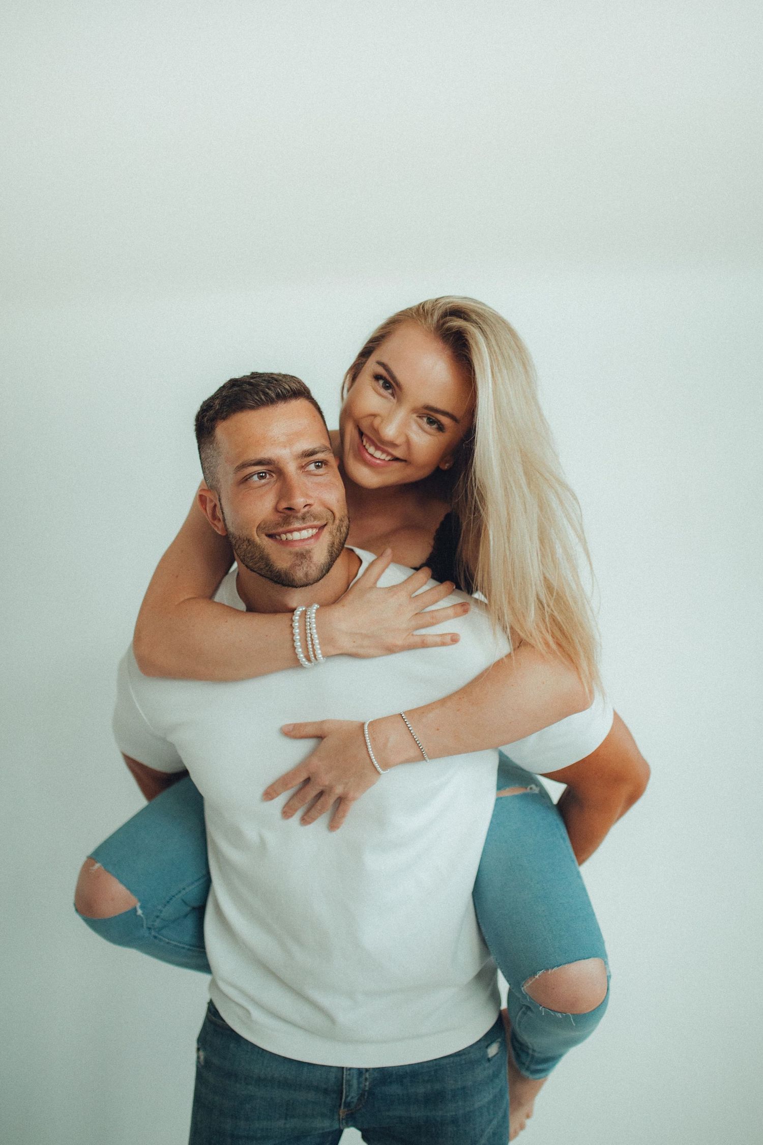A playful piggyback ride moment captured against a light background indoors.