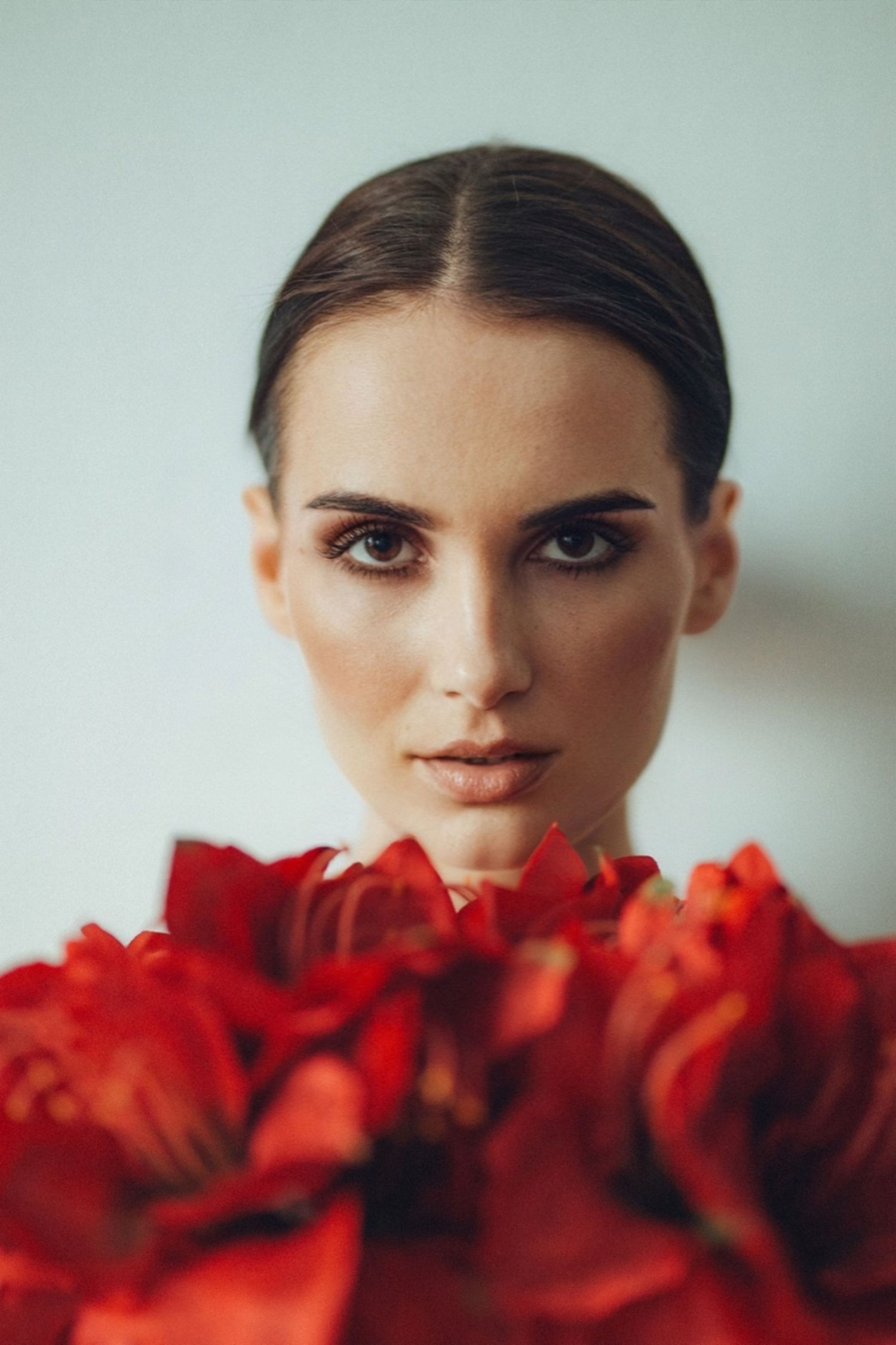 Close-up beauty portrait with red roses and soft dramatic lighting.
