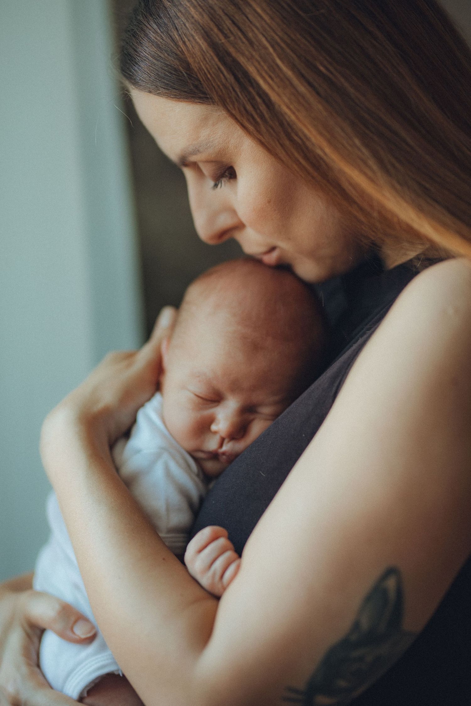 A tender mother gently holds her sleeping newborn baby close to her chest, sharing a peaceful bonding moment.