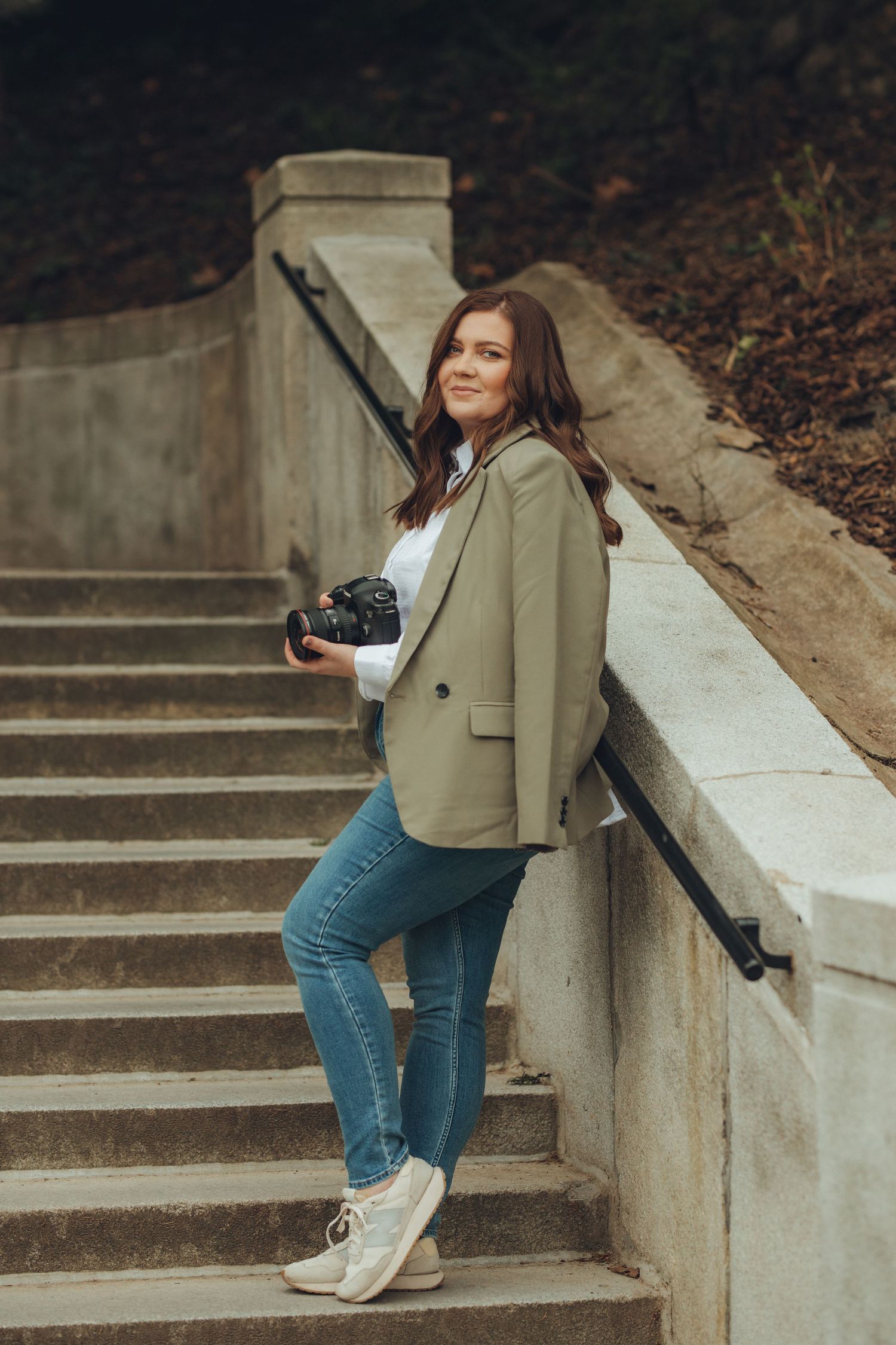 Fashion photoshoot on concrete steps featuring casual denim and beige jacket outfit.
