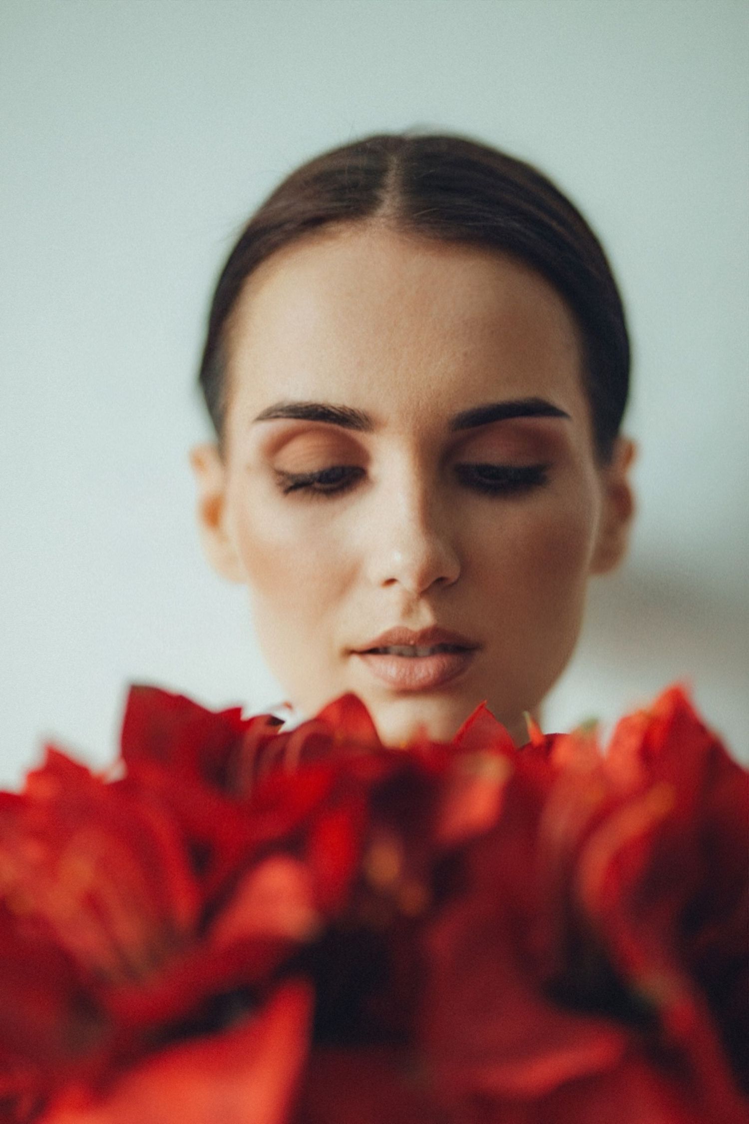 Artistic beauty portrait with vibrant red roses in soft focus.