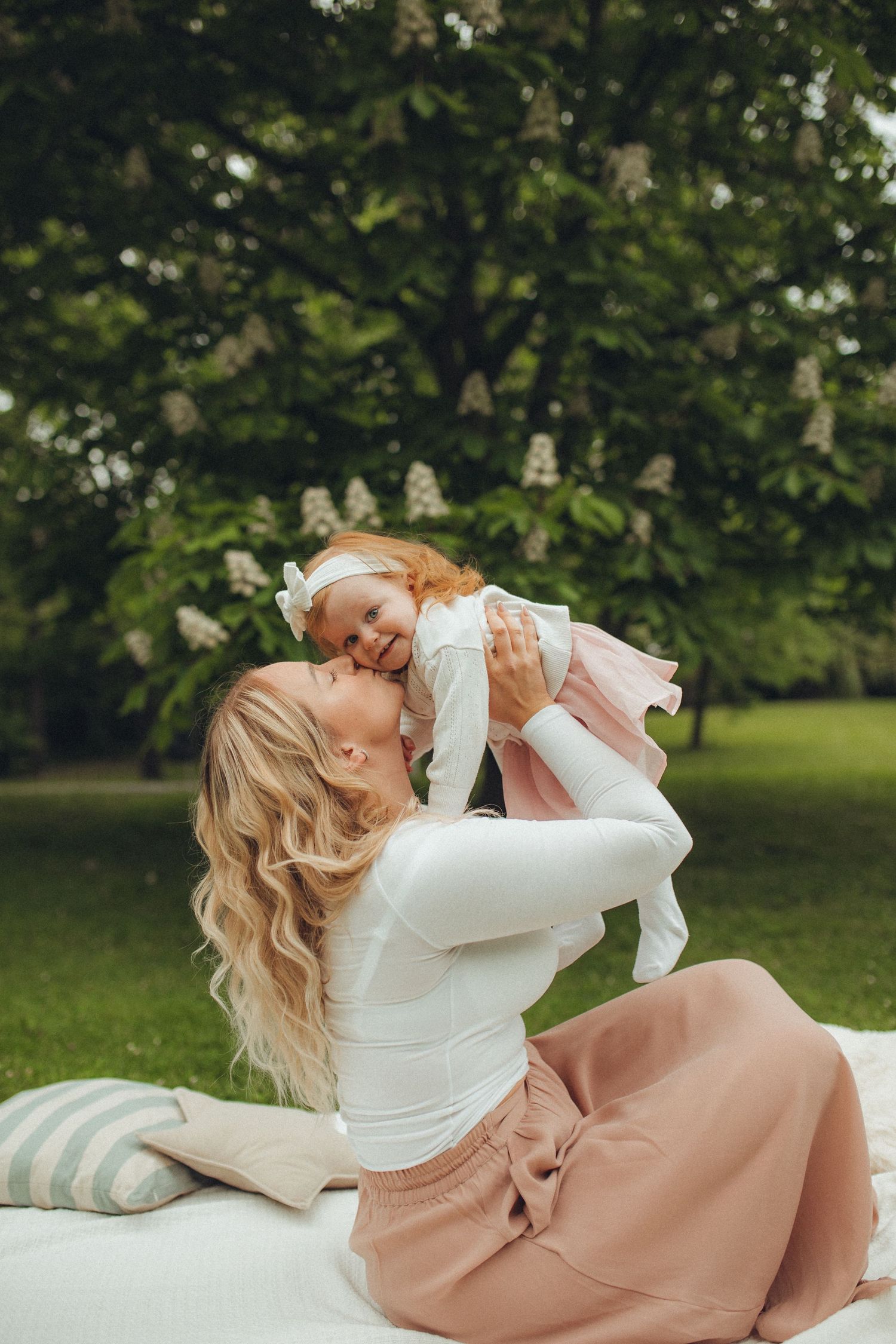 Woman in white top and pink skirt lying on grass in a romantic outdoor photoshoot.