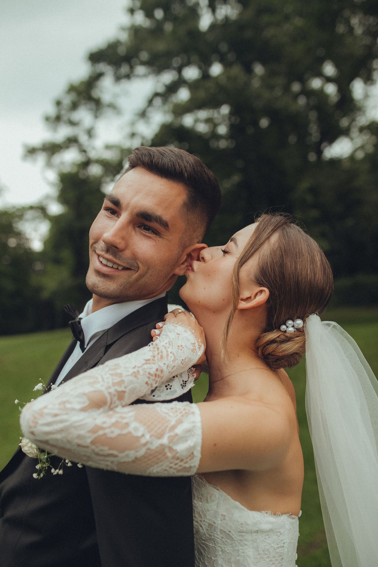 Candid wedding portrait showing playful moment between newlyweds in outdoor setting.