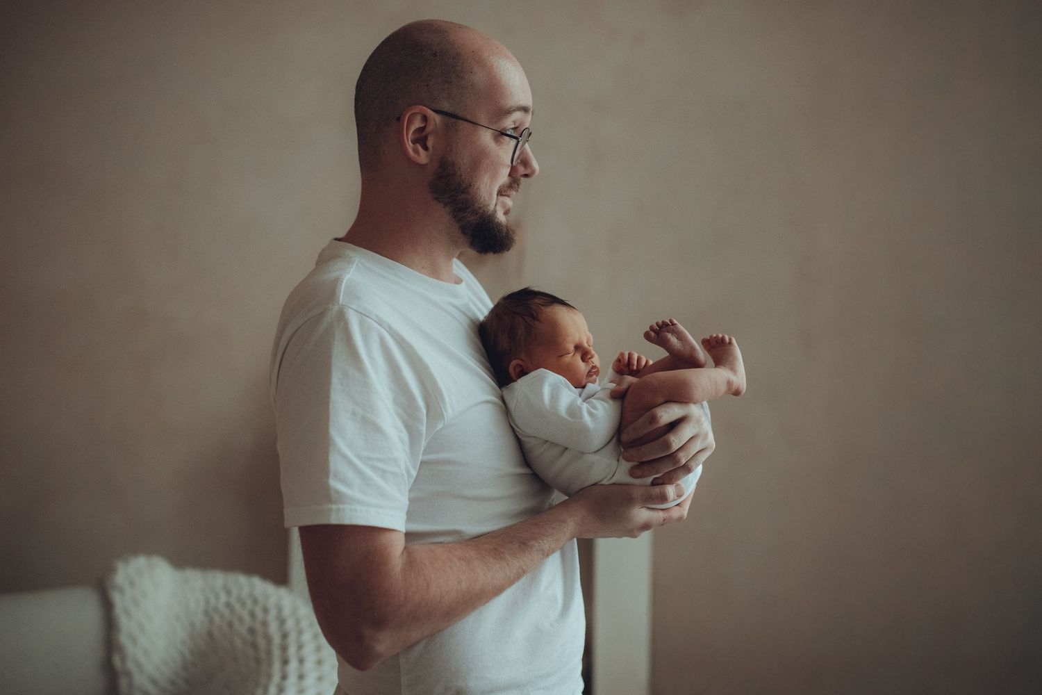 A person in a white shirt holds and comforts a sleeping newborn baby in a series of tender moments.