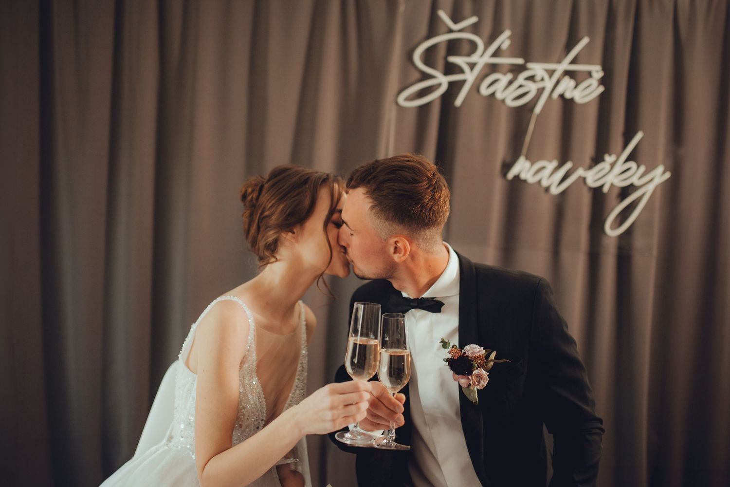 Wedding couple sharing intimate moments under decorative script wall signage.