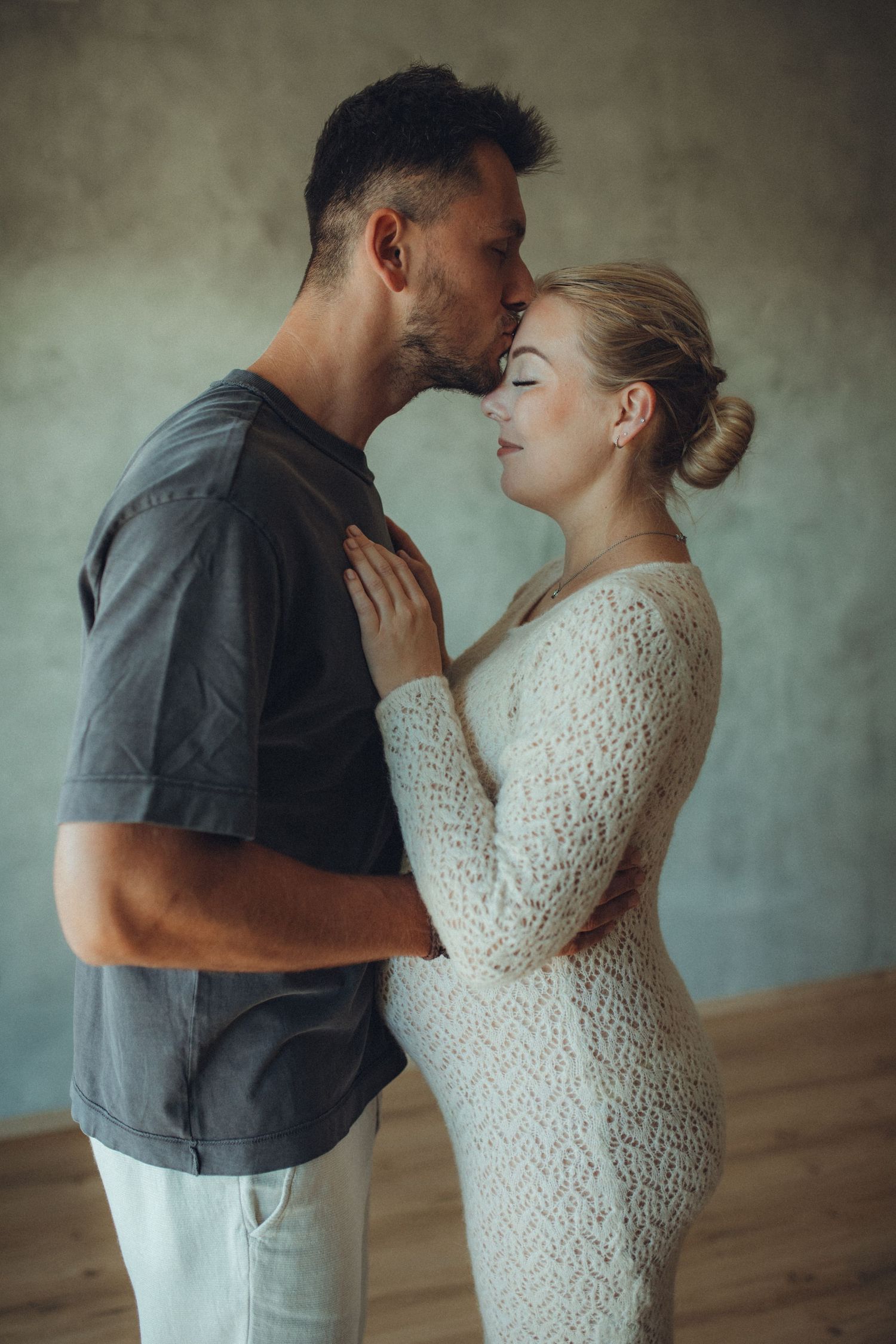A couple shares an intimate moment in a series of artistic photos against a textured gray background.