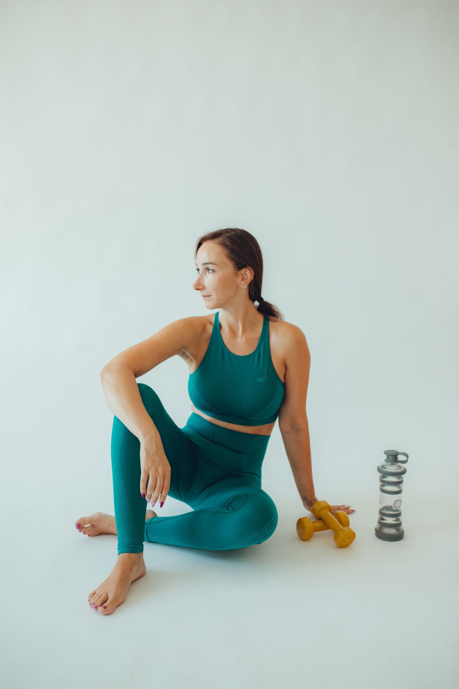 Fitness scene with person in teal activewear seated next to exercise equipment.