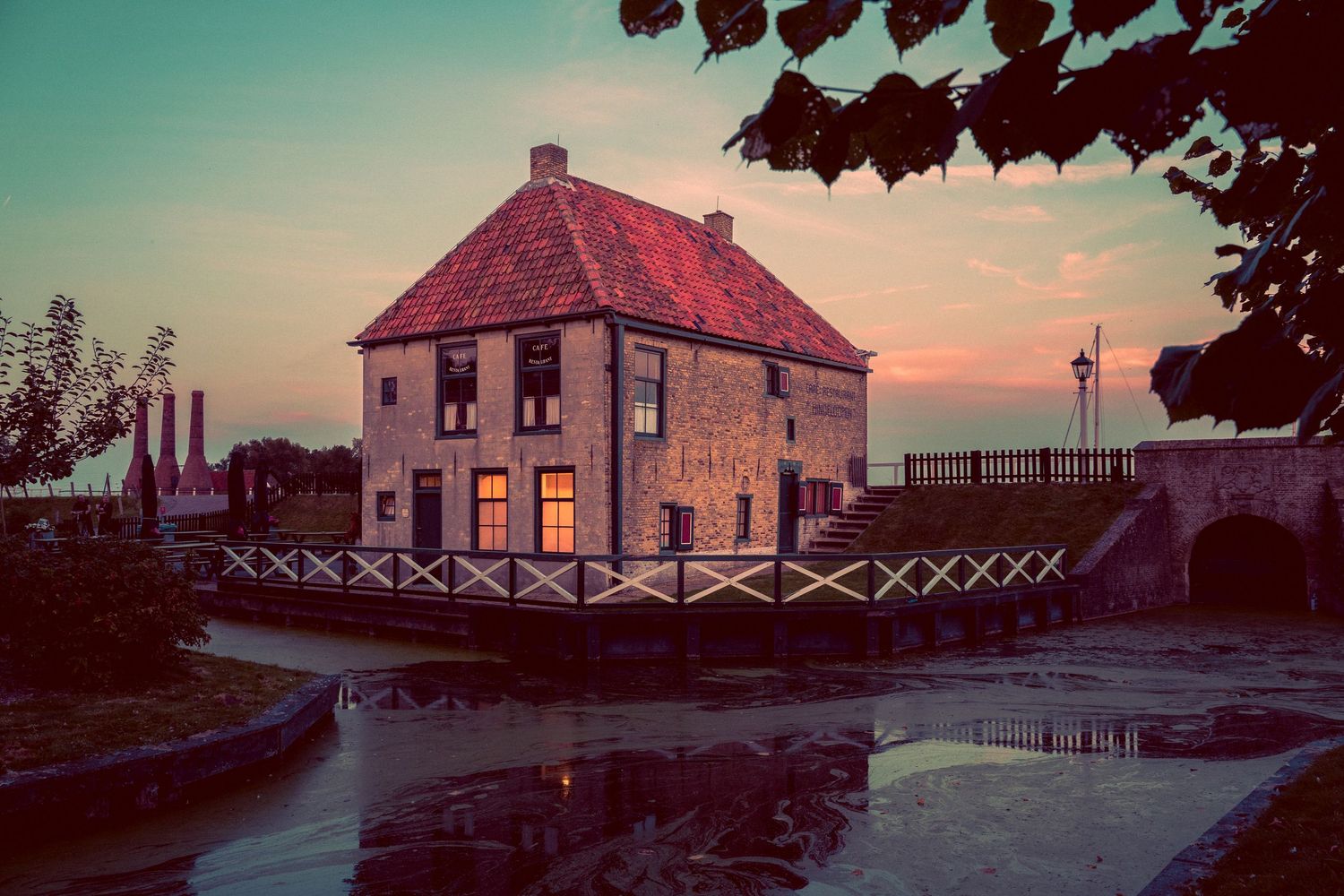 Panoramic view of rustic farmhouses at sunset with warm lighting and fences.