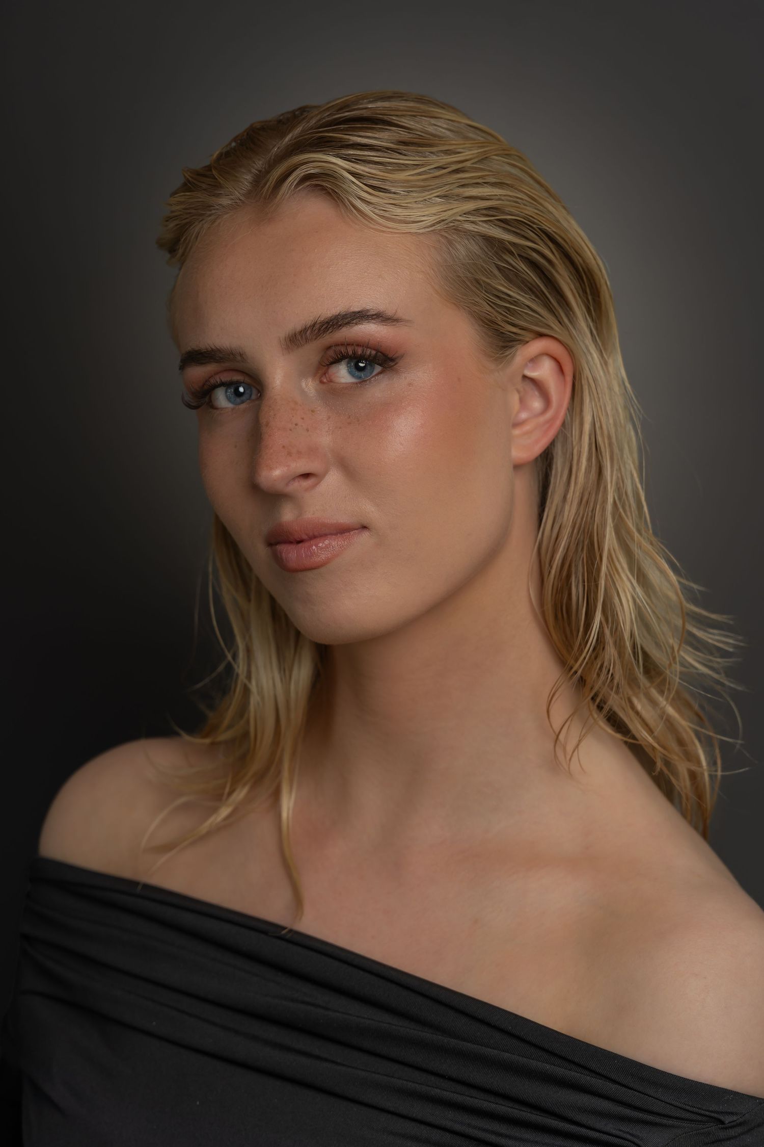 Dramatic studio portraits with moody lighting and wet-look blonde hair styling.