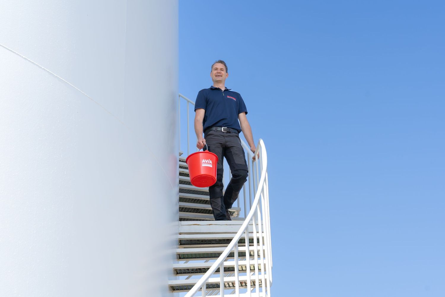 Person ascending modern white floating staircase against bright blue sky.