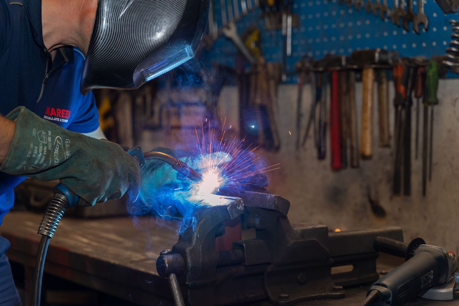 Industrial welding equipment creating bright blue sparks in a workshop setting.