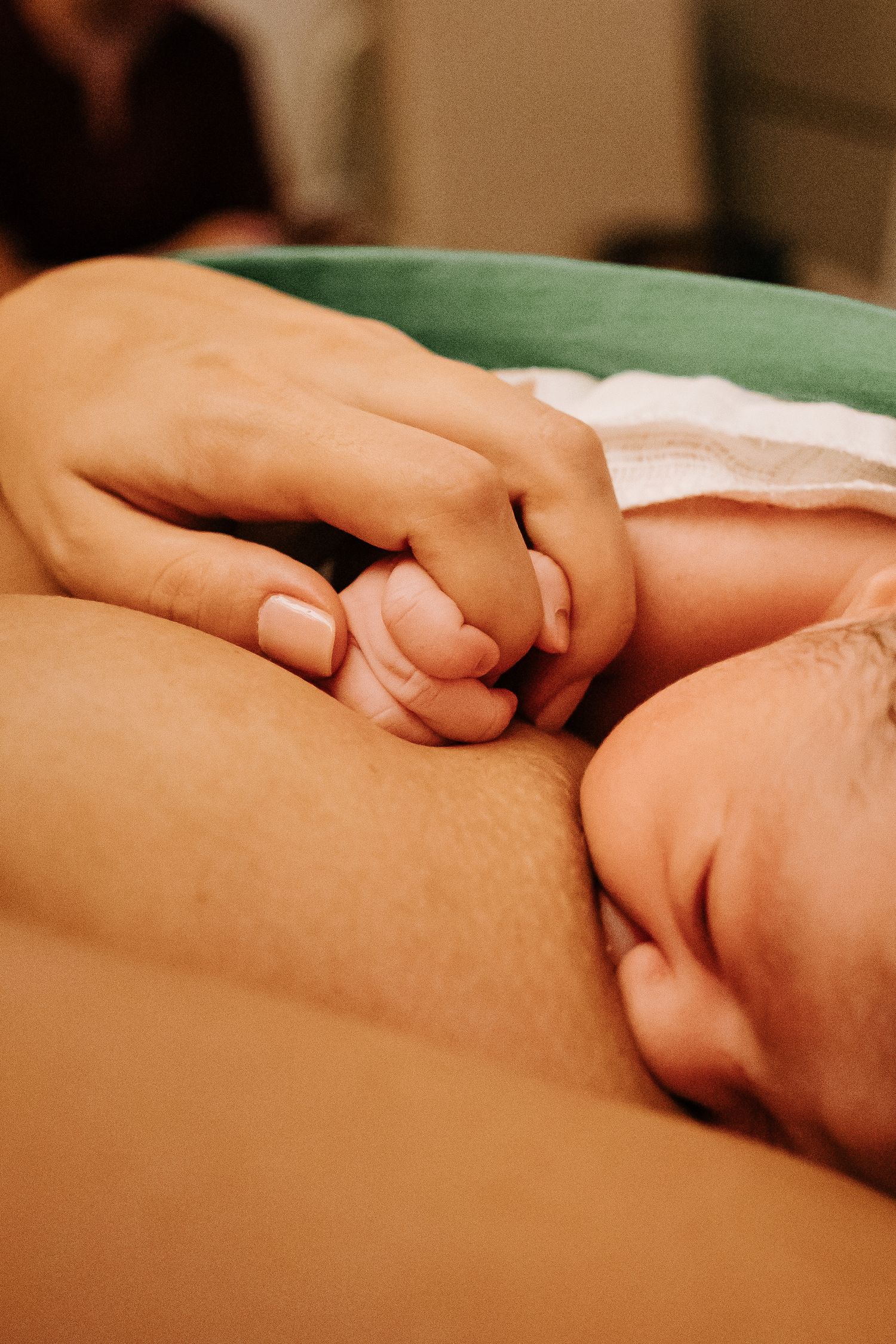 A baby's tiny hand grasps a caregiver's finger in an intimate moment of bonding.