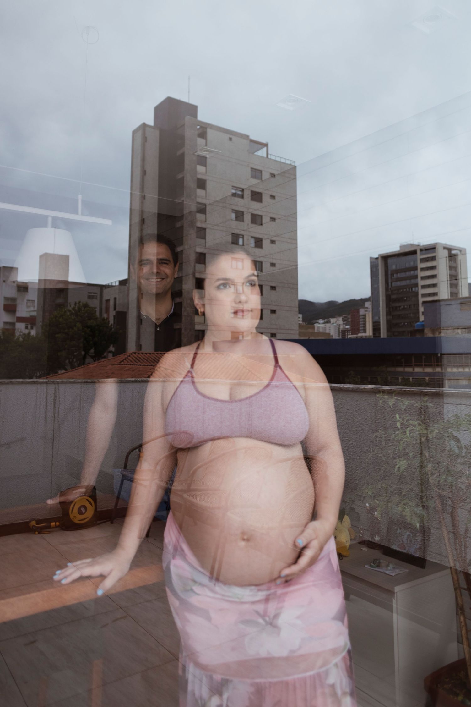 A diaphanous pink fabric creates a ghostly double exposure effect against an urban backdrop of apartment buildings.