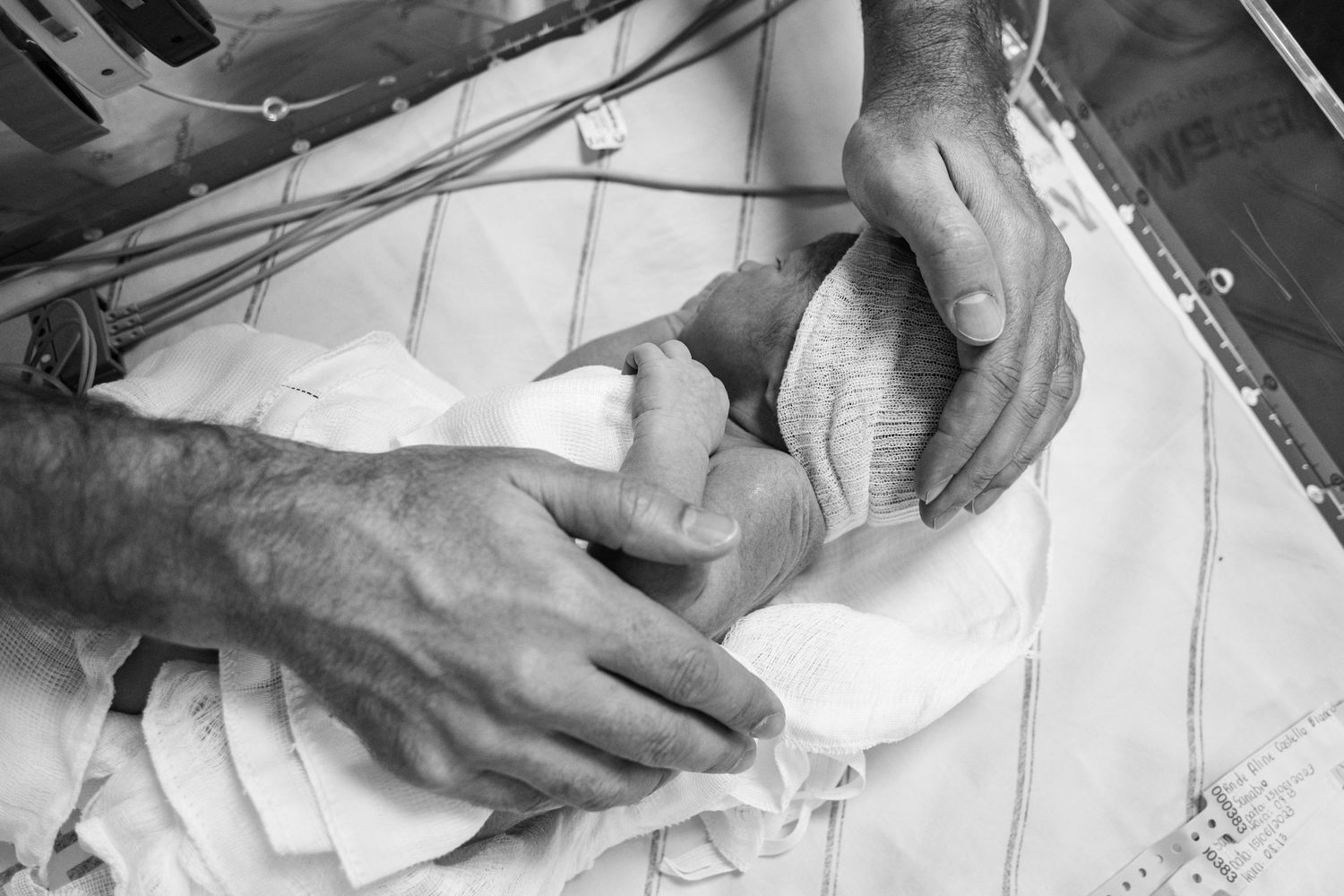 Black and white image of medical staff handling newborn baby wrapped in hospital blankets.