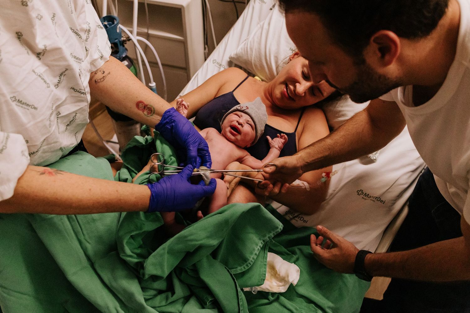 Medical staff examine a newborn baby wrapped in green hospital linens during first moments after birth.