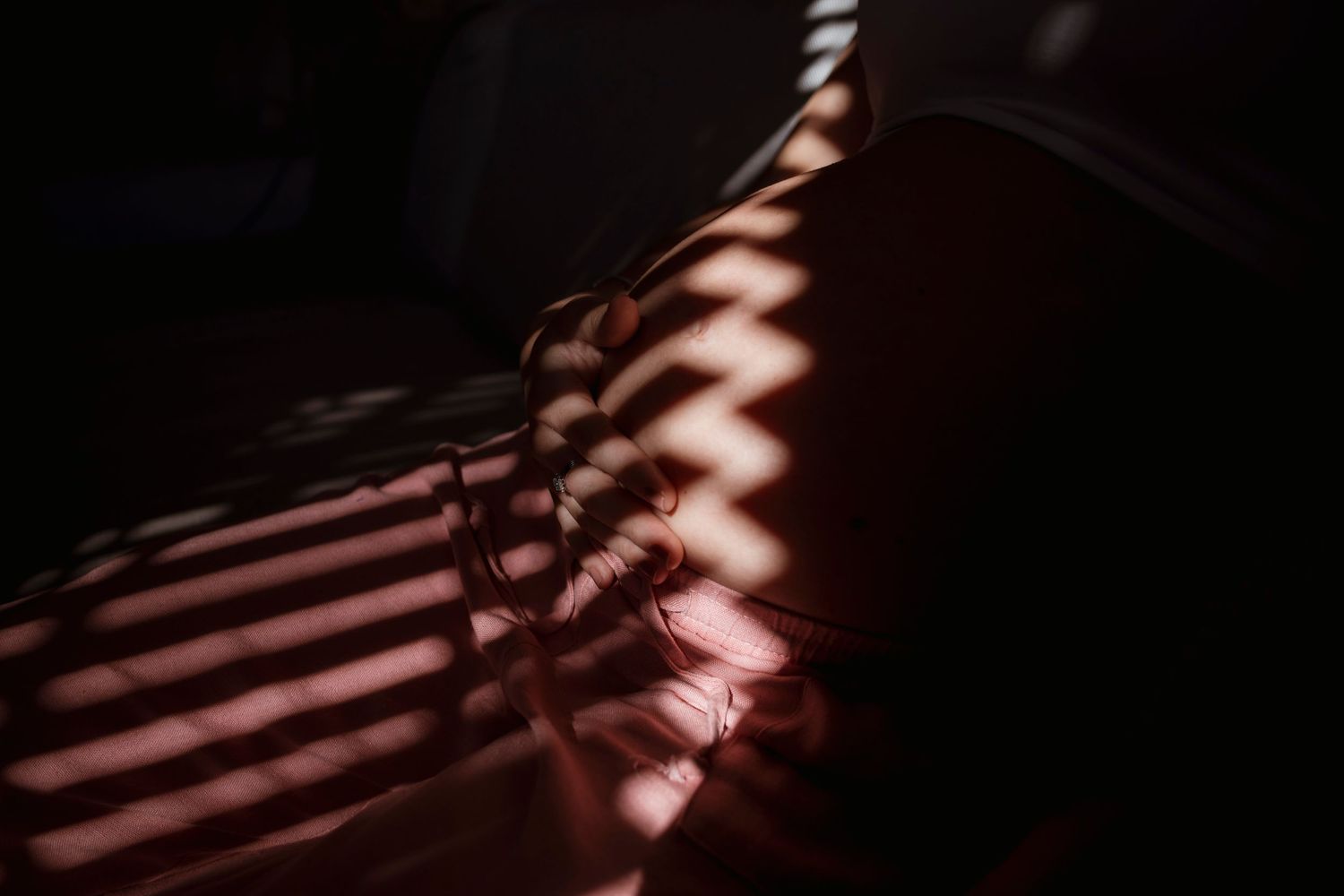 Abstract shadows and light patterns create a striped pattern on a dark surface in dramatic lighting conditions.