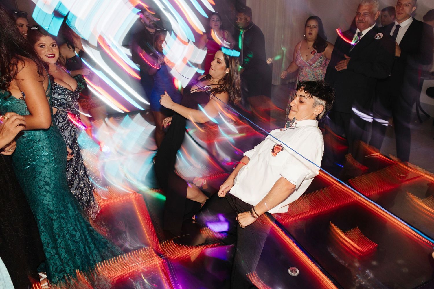 Dynamic party scene with dancers under red and blue lighting on a dance floor.