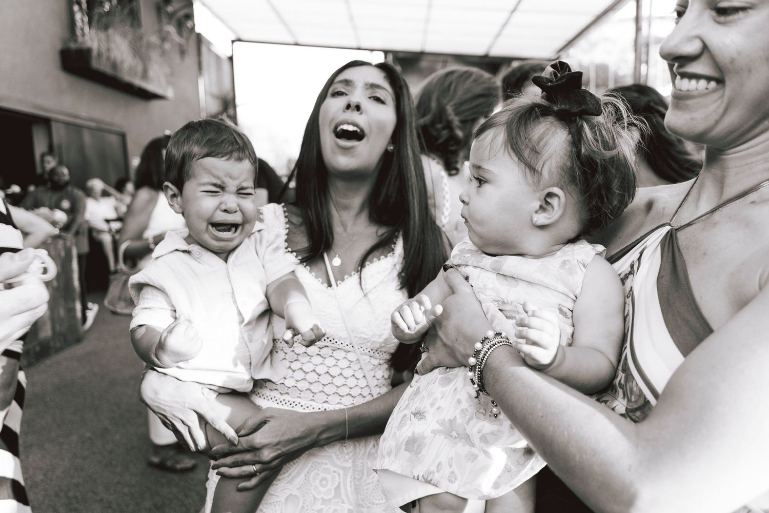A candid black and white photo of people laughing together at a social gathering.