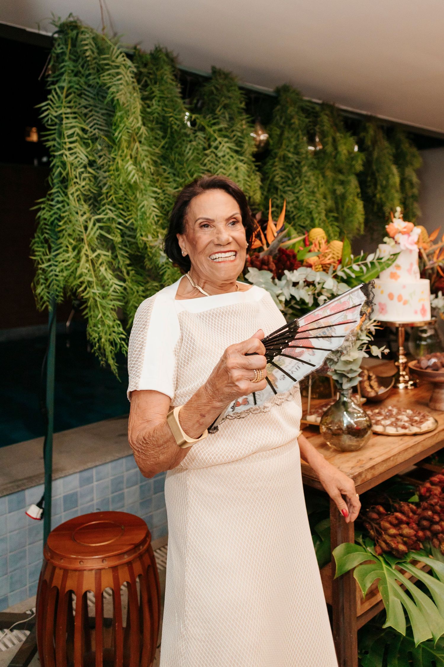 Person smiling while holding decorative fans at tropical-themed party.