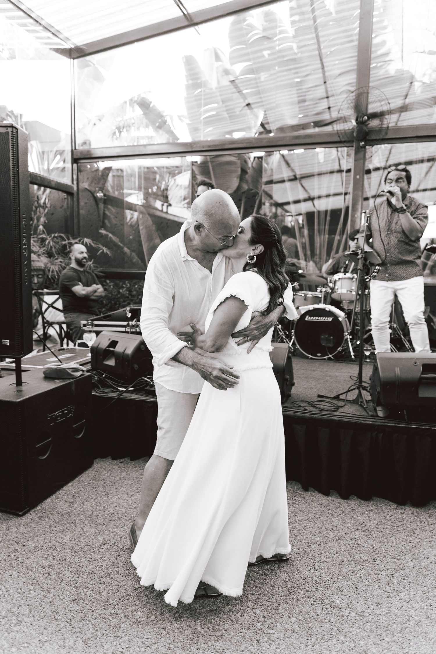 A couple shares a romantic dance moment at an outdoor wedding reception with a live band performing.
