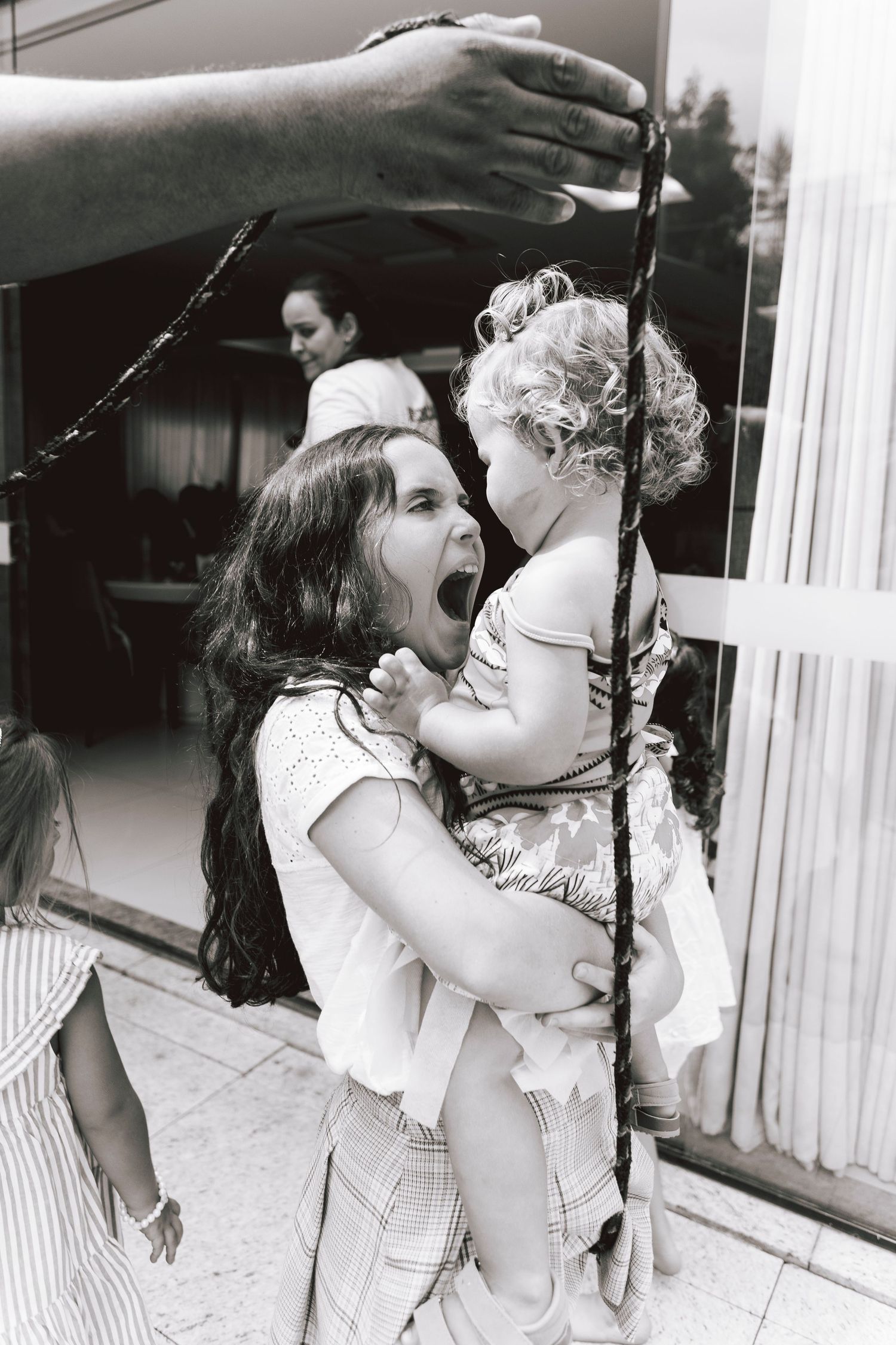 Black and white photo capturing playful interaction with baby on swing set.