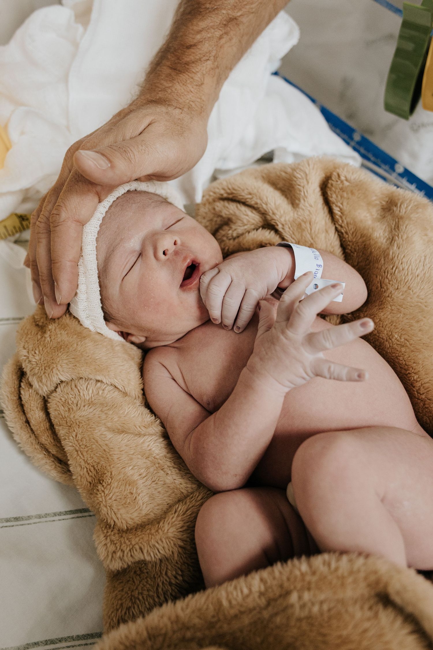 Sleeping newborn wrapped in cozy beige blanket during medical examination.