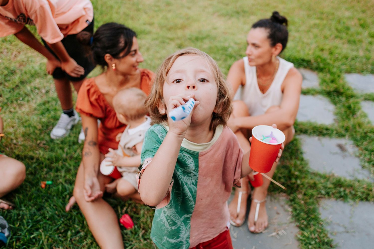 A child enjoying a refreshing drink outdoors during a summer gathering.