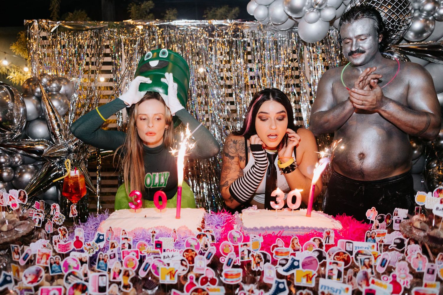 Crowded dance party with silver balloons and colorful lights creating a festive atmosphere.