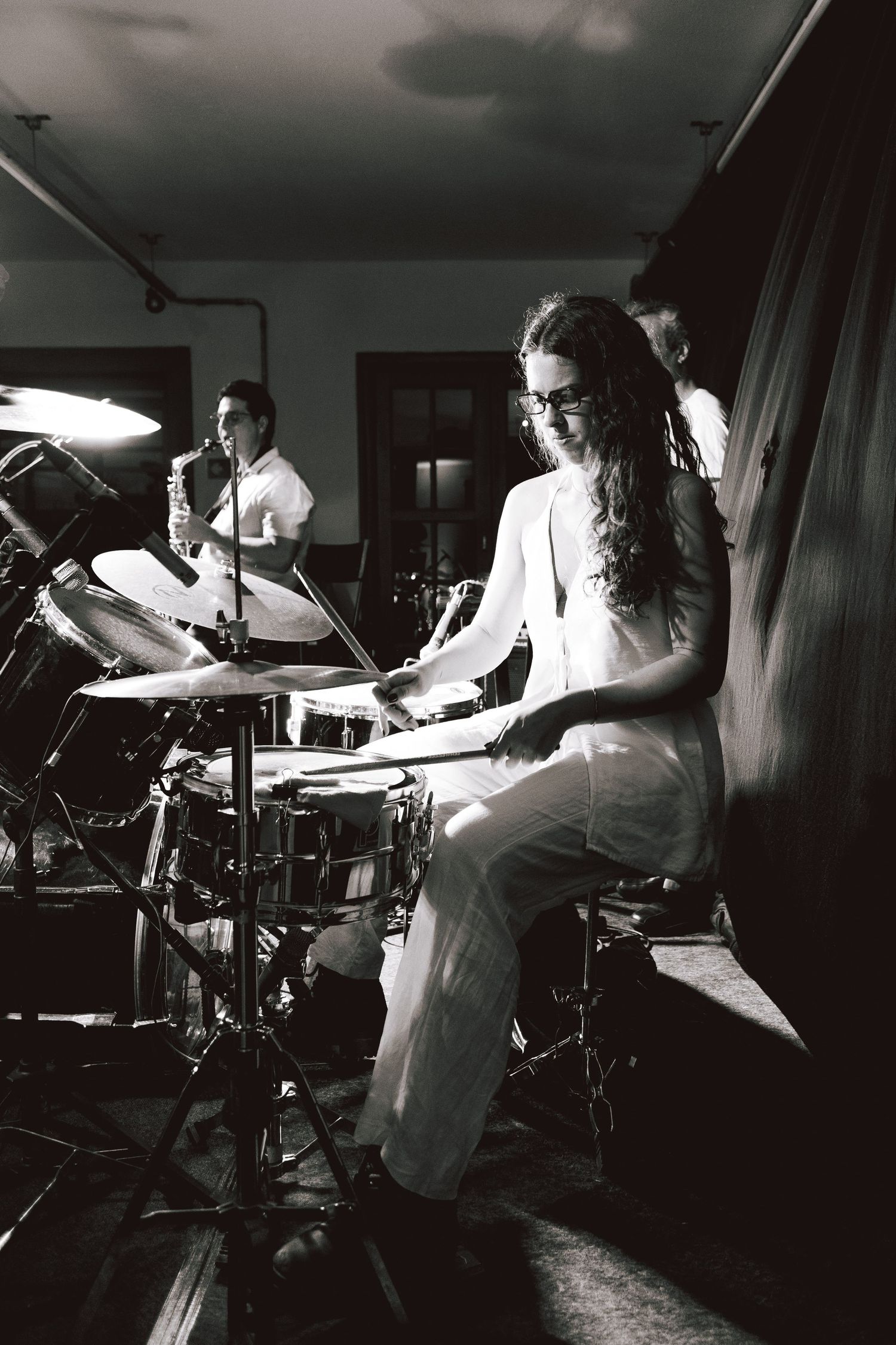 A drummer performs energetically in a dimly lit studio space, captured in a dramatic black and white photo sequence.