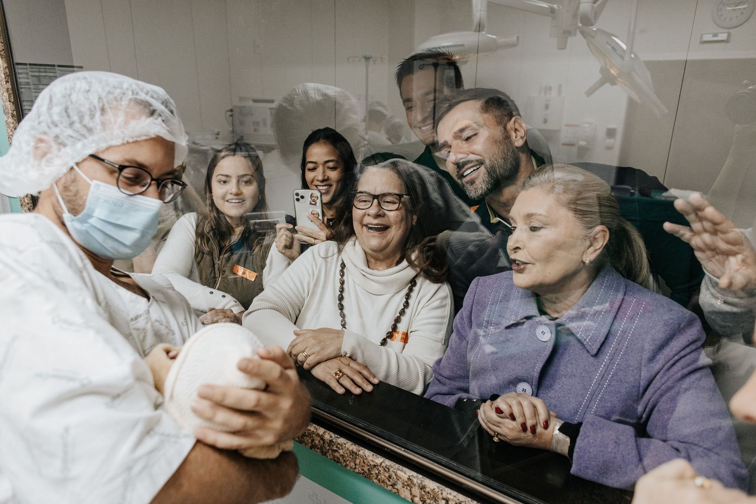 Medical staff and family members share joyful moment in hospital delivery room setting.